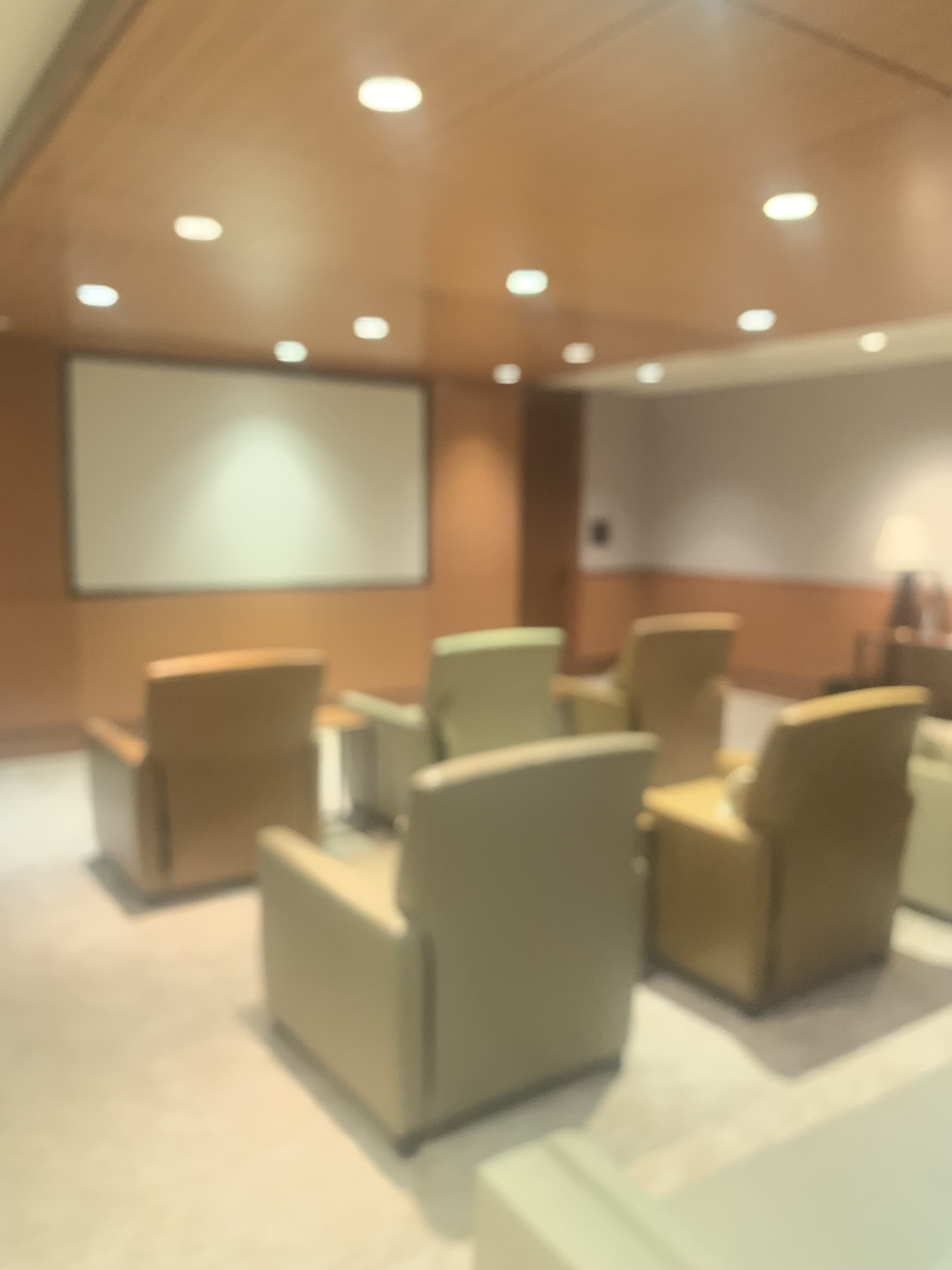 Media room with a wall-mounted big screen and four individual arm chairs.