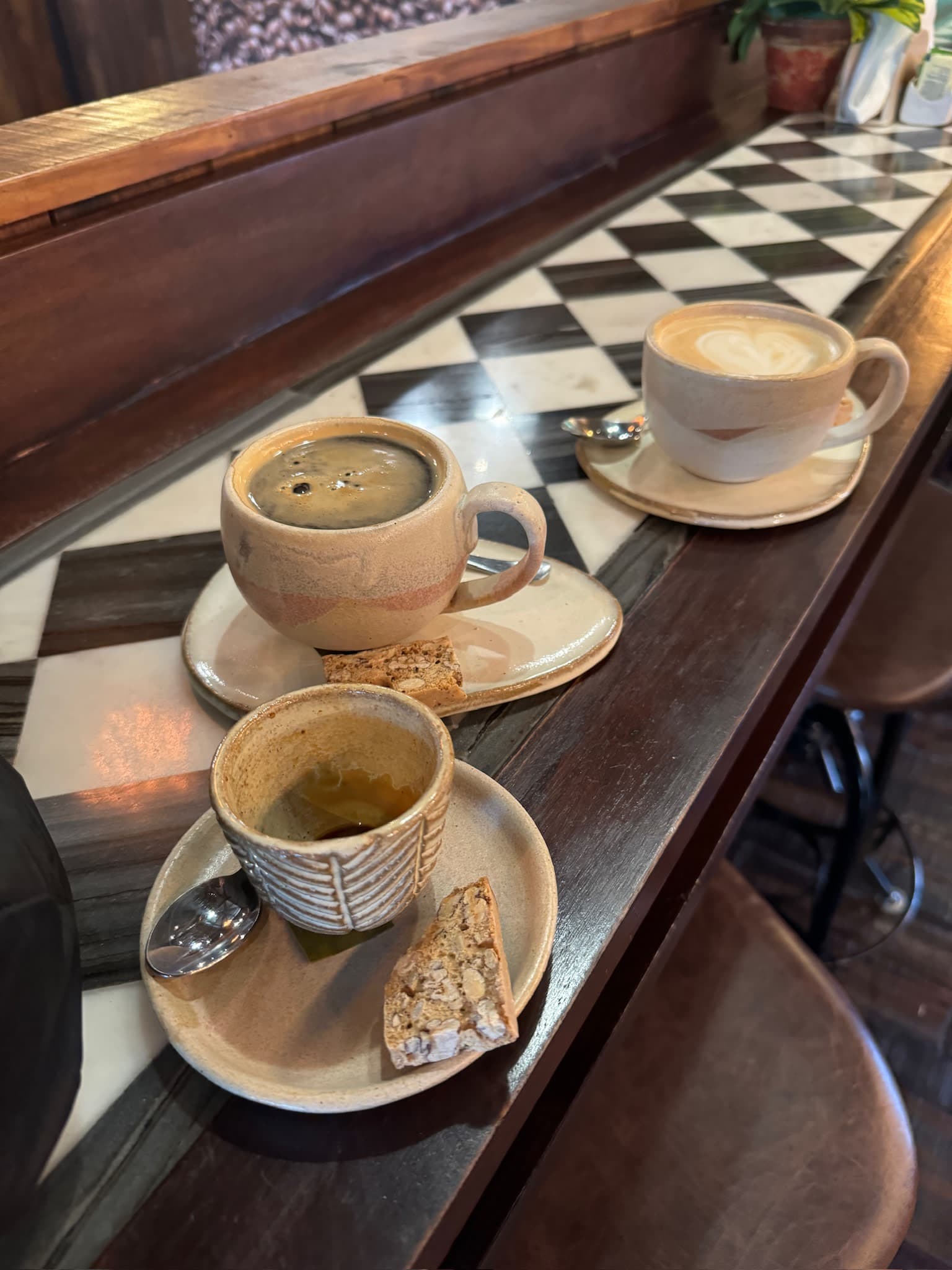 Cappuccinos on a checkered wooden bar.