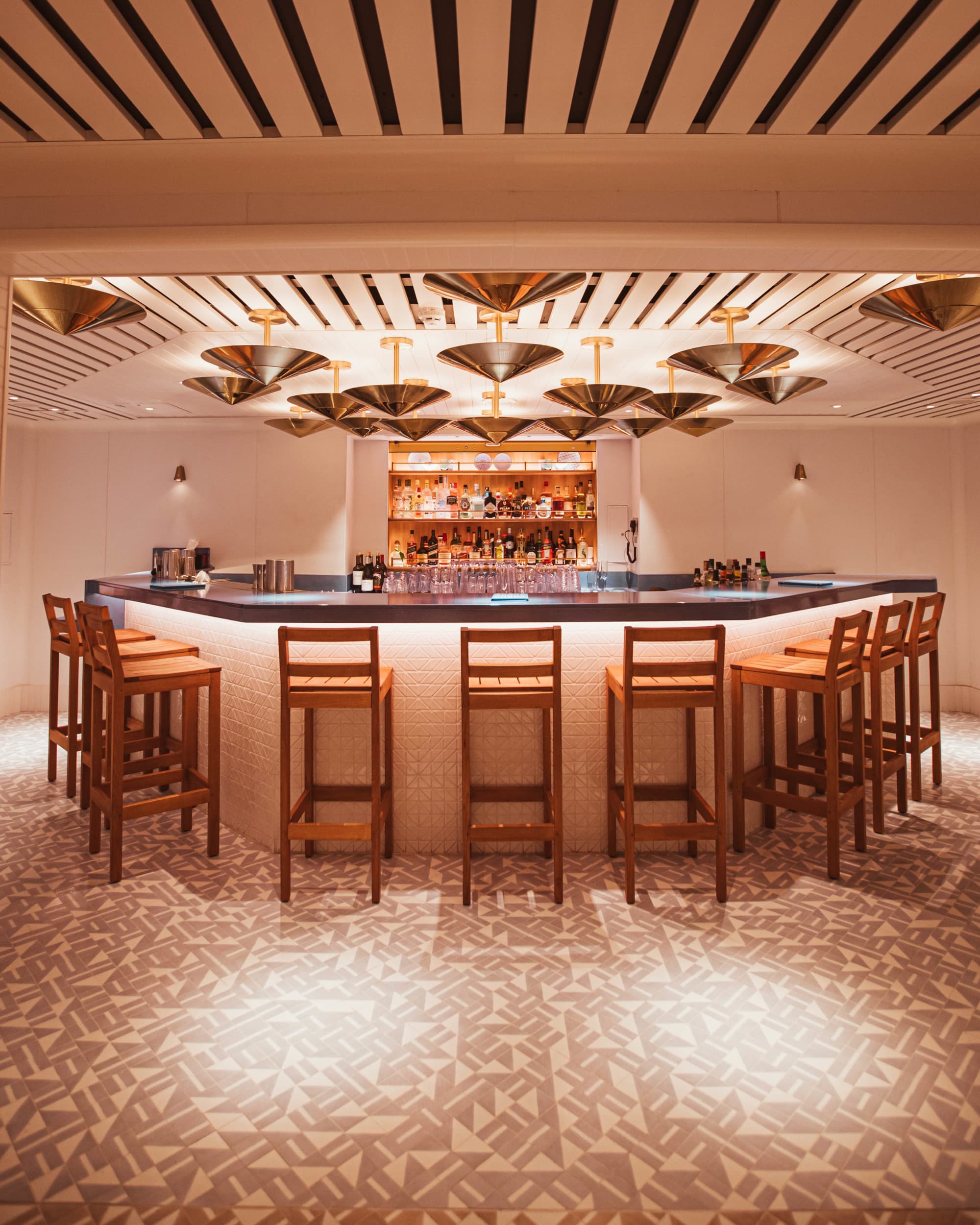 A view of an upscale bar area with brown furniture and warm lighting on the cruise ship.