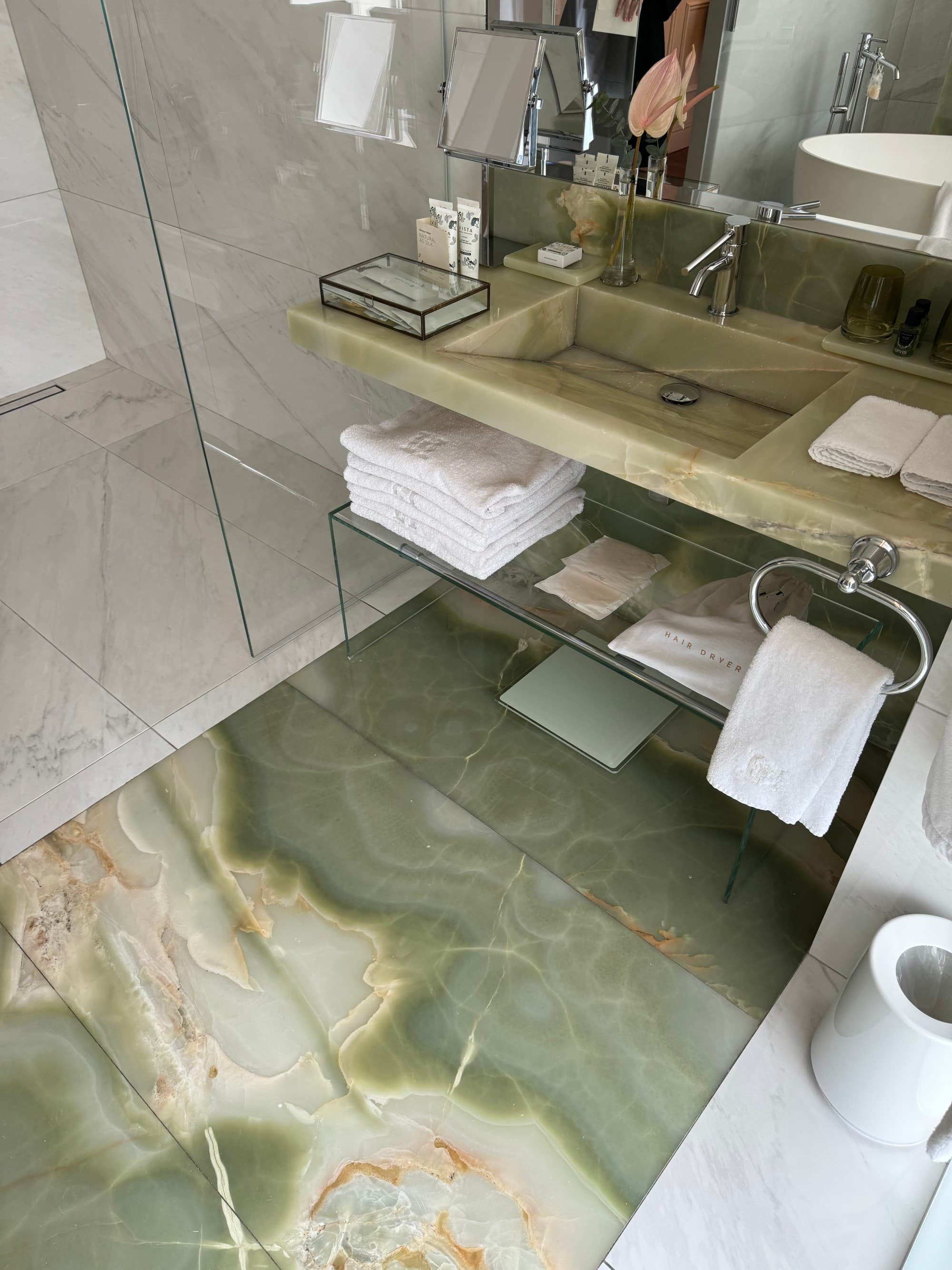 A hotel bathroom with intricate, green stone-tiled floors and a sink.