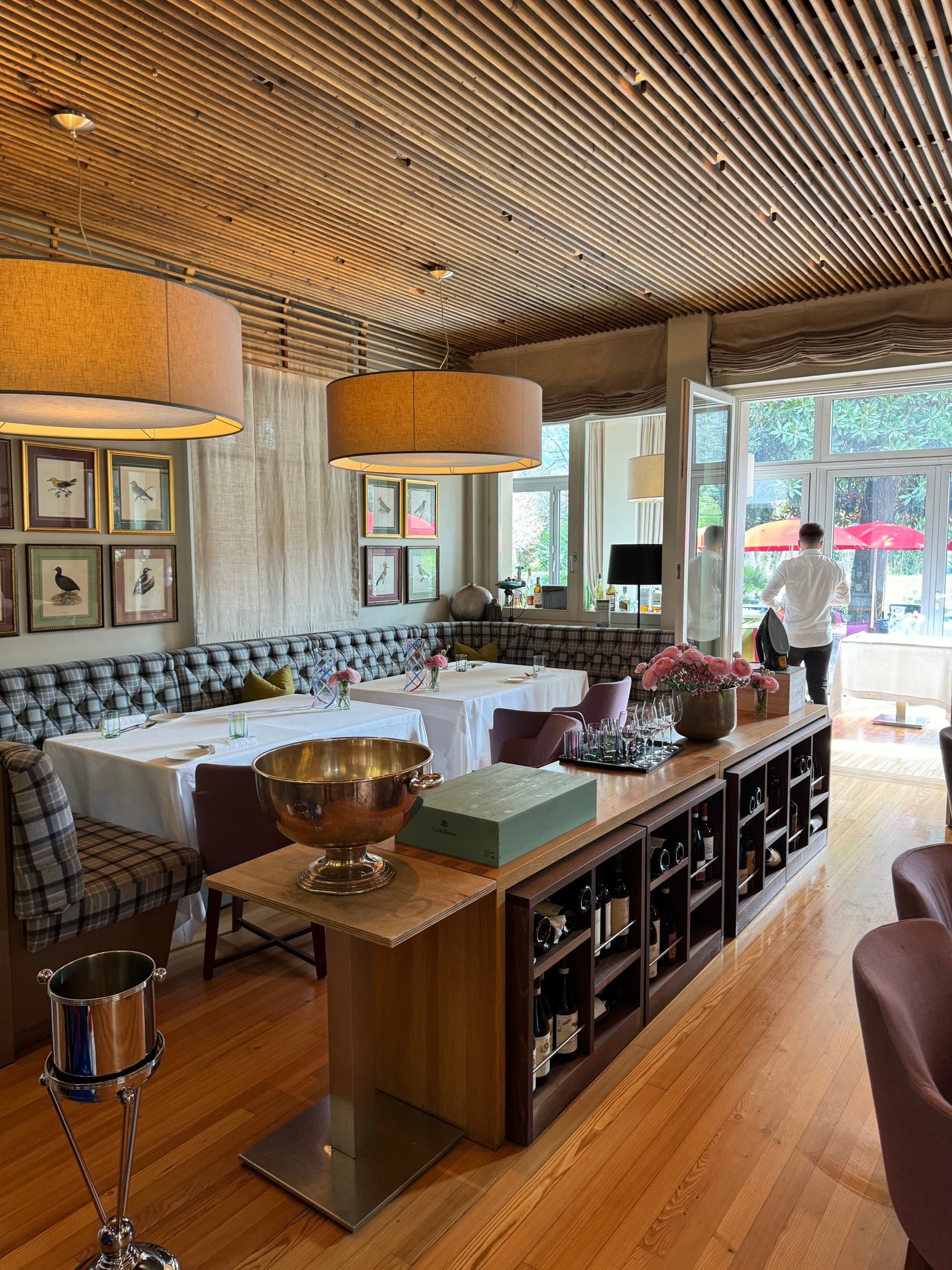 A restaurant seating area with wood paneled walls and ceilings and cushioned booths to eat at.