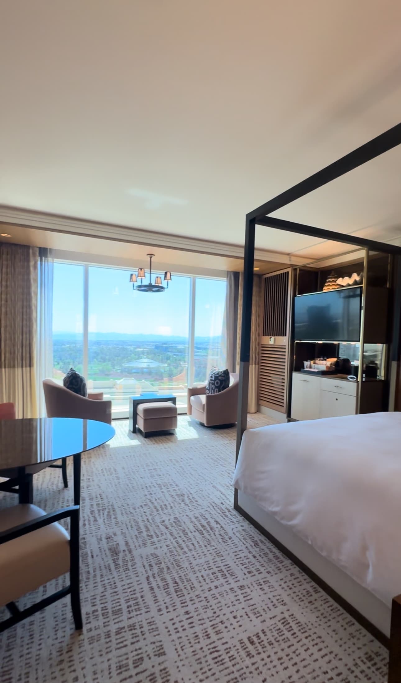 A view within the hotel room, with the corner of the bed, furniture, and floor-ceiling windows showcasing a view of Las Vegas below.