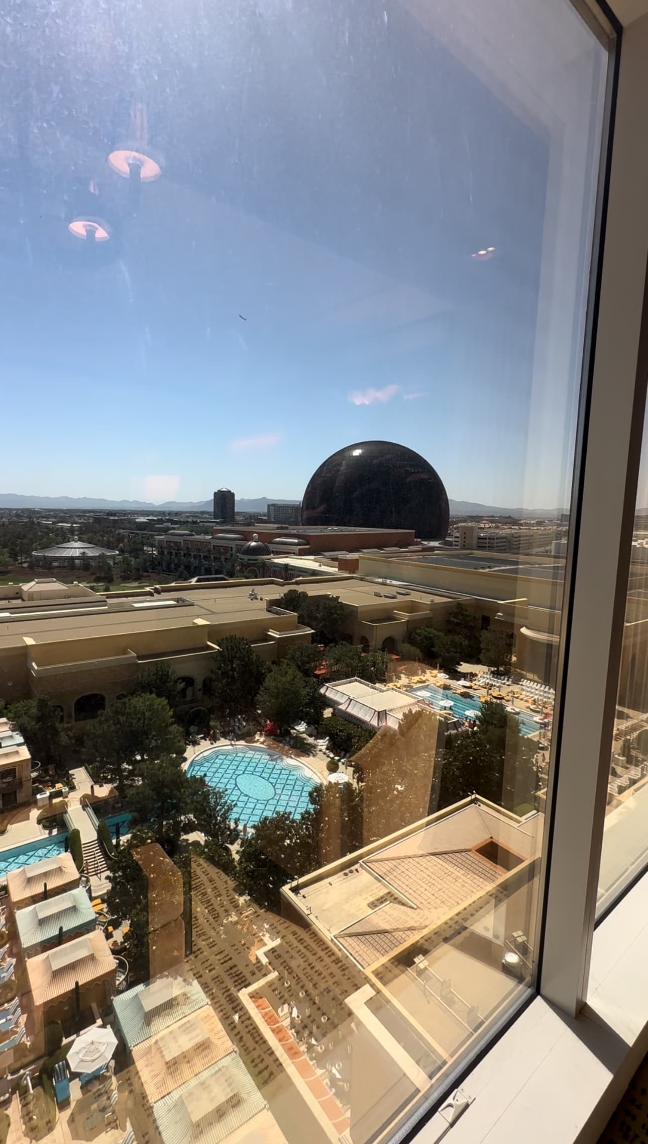 A view from the hotel window looking down at the pool and the Las Vegas Sphere.