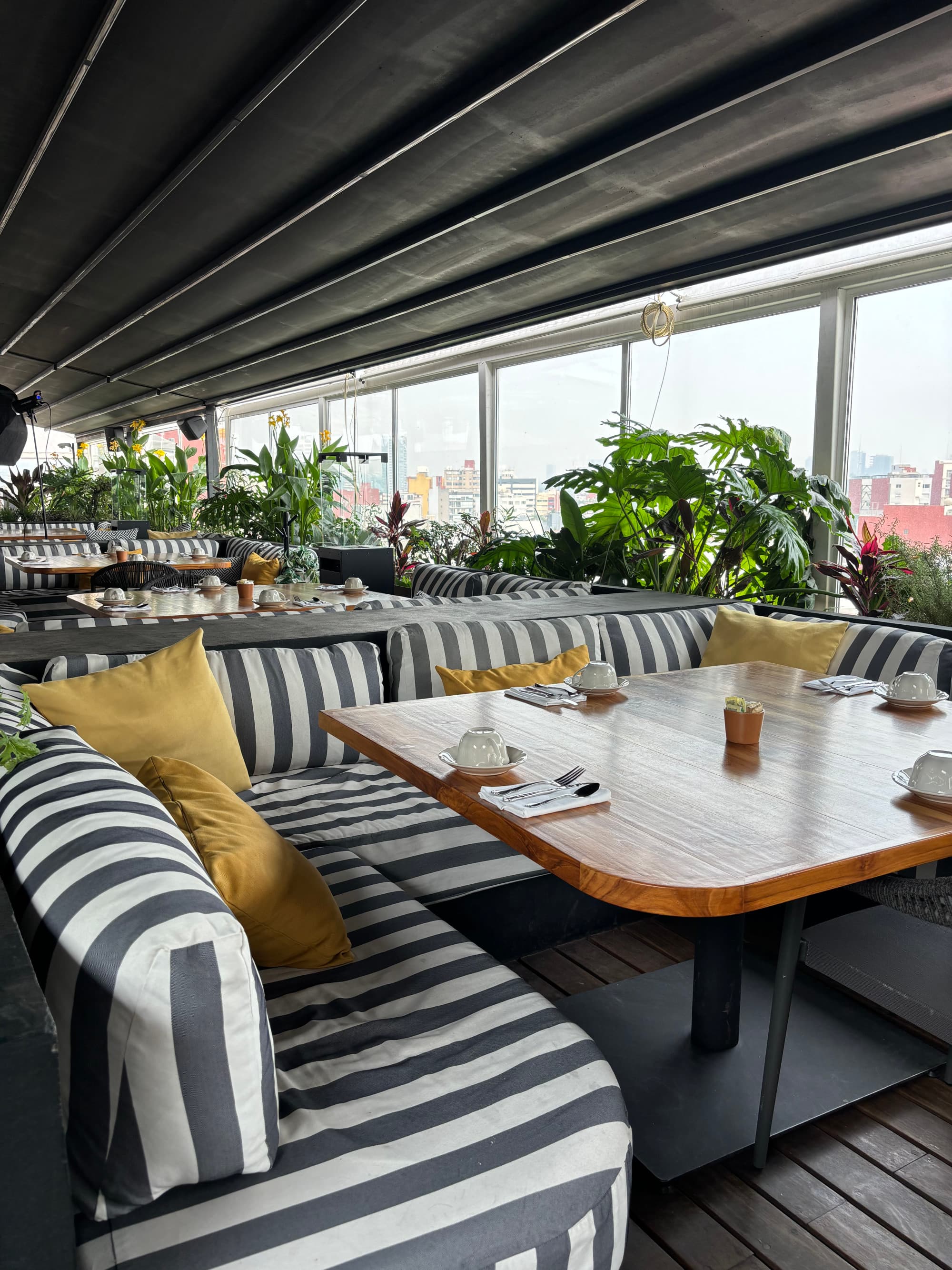 A dining area comprised of soft benches, wooden tables and views of Mexico City.