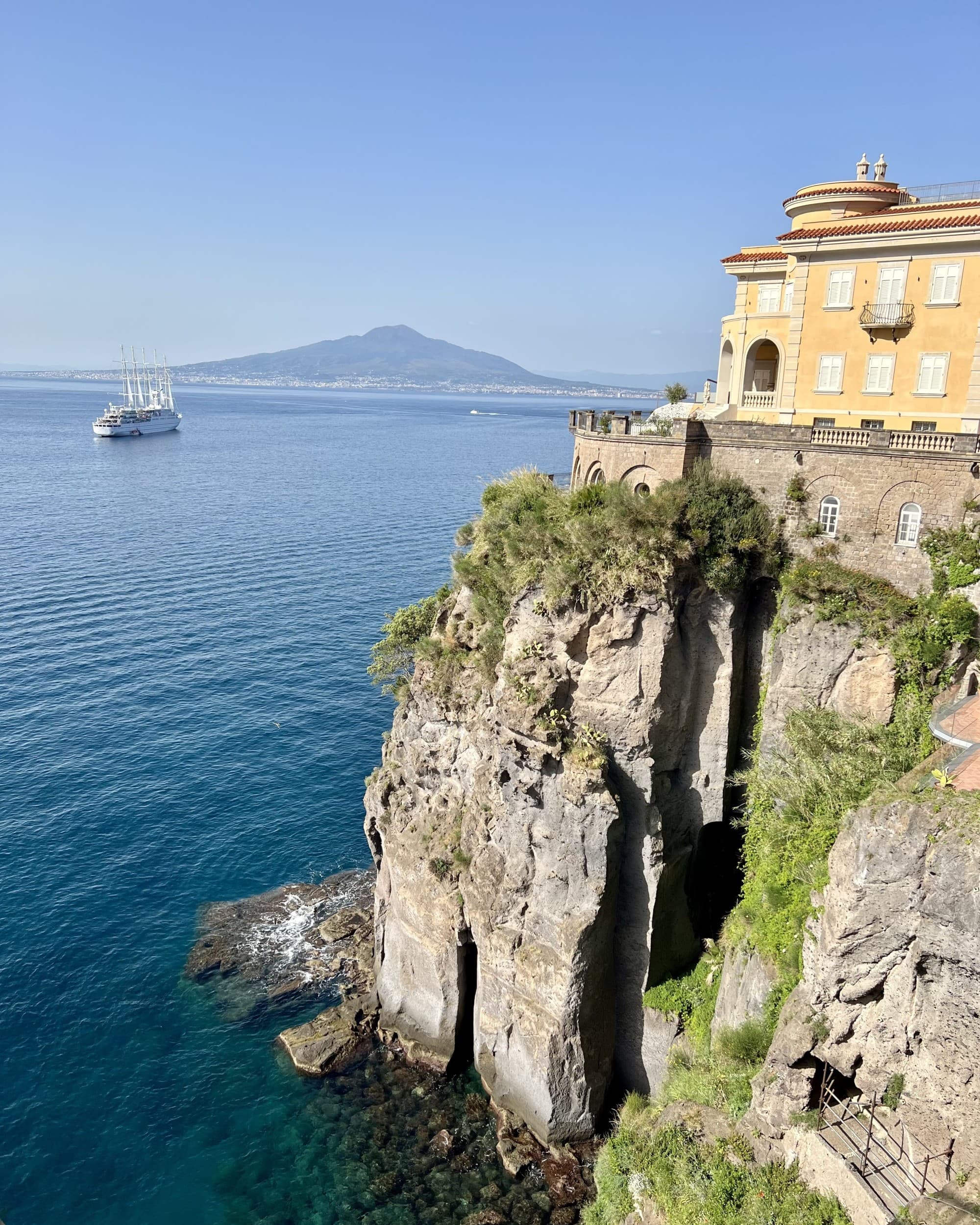 A yellow house on a cliff over the ocean