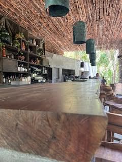 A view of the wooden bar at Nomade Tulum with hanging lamps