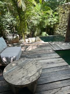 A view of the hotel room's plunge pool and wooden deck surrounded by lush greenery