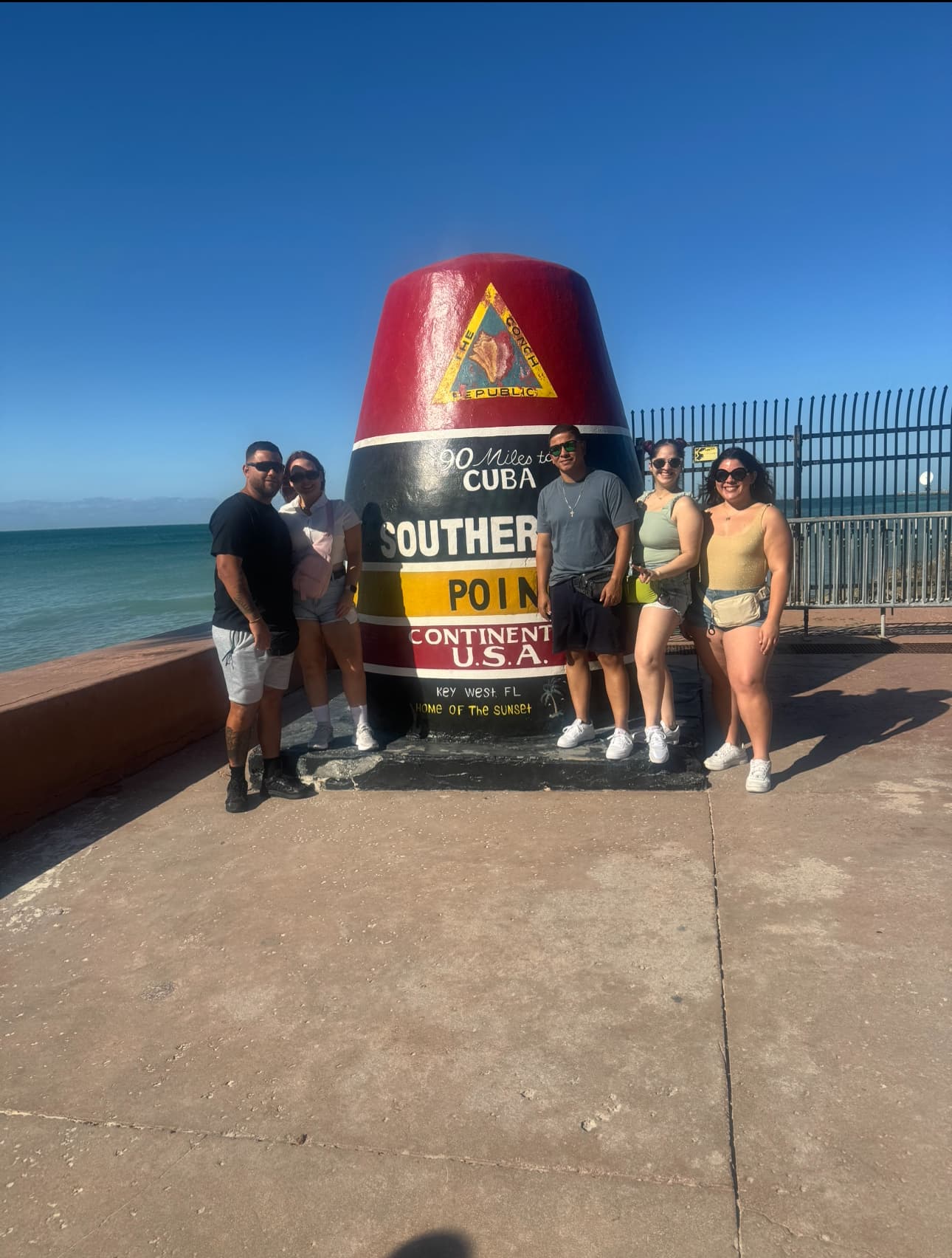 Travel advisor and friends in front of a Key West 90 miles to Cuba buoy.