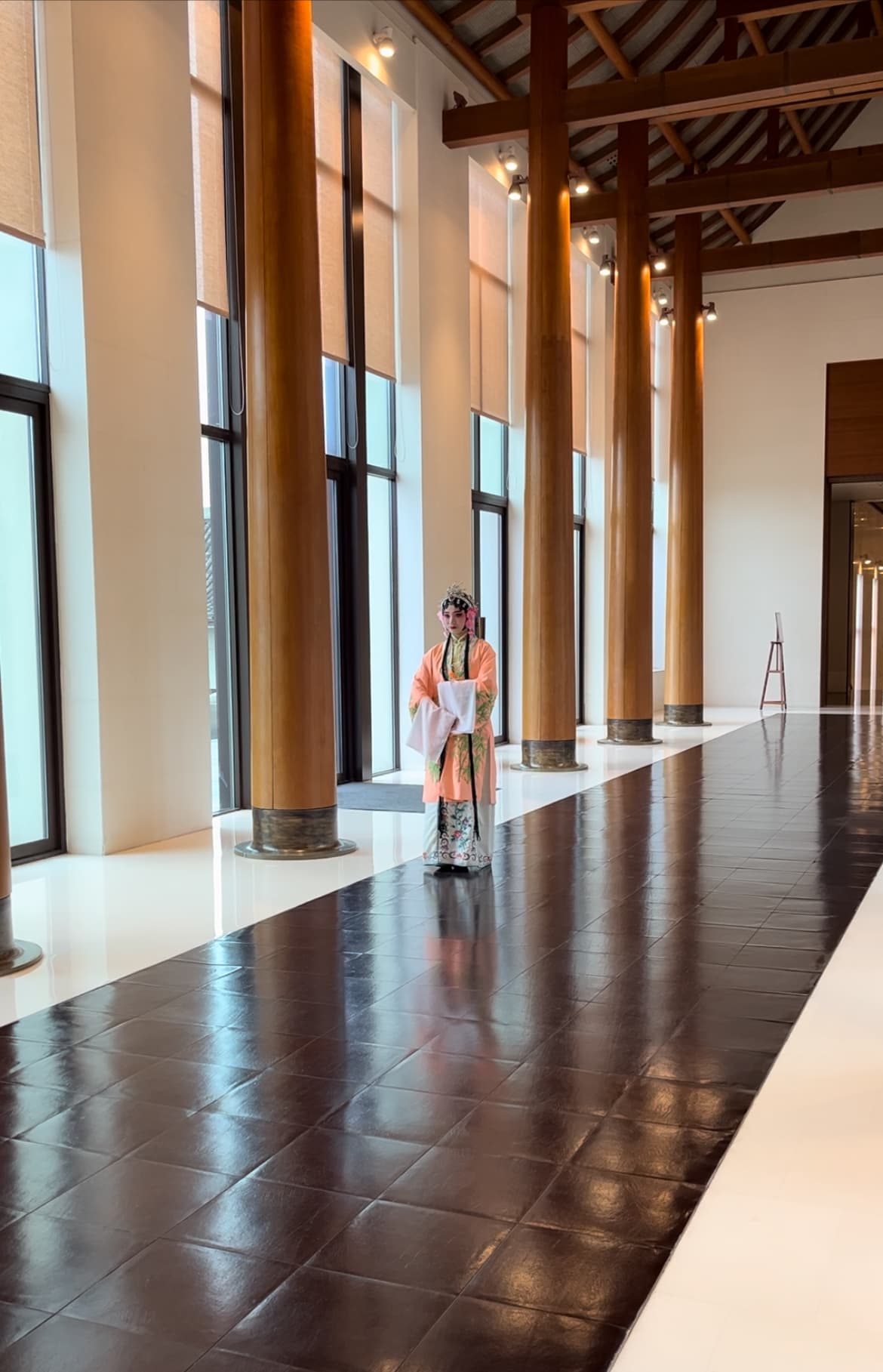 A person in a traditional outfit in a long indoor hallway