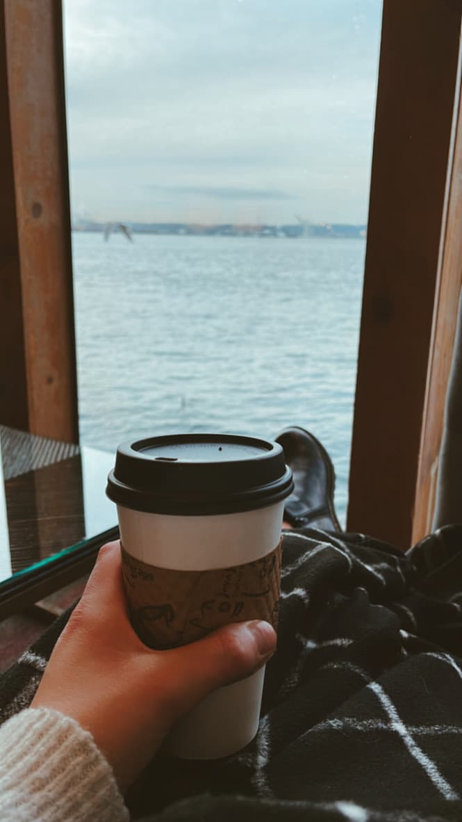 Advisor holding a cup of coffee in front of a window looking at a body of water