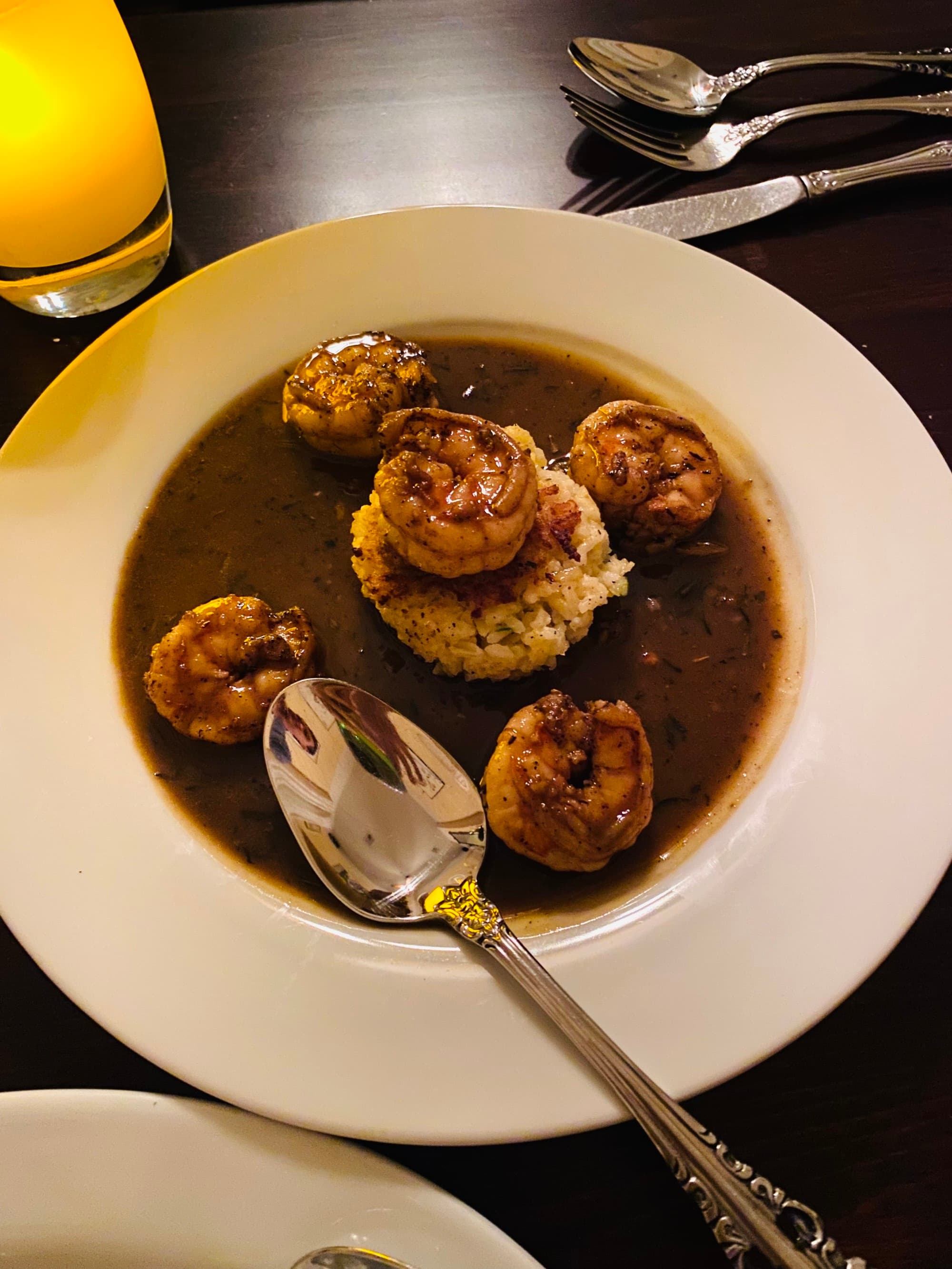 A white bowl with shrimp and rice in a sauce.