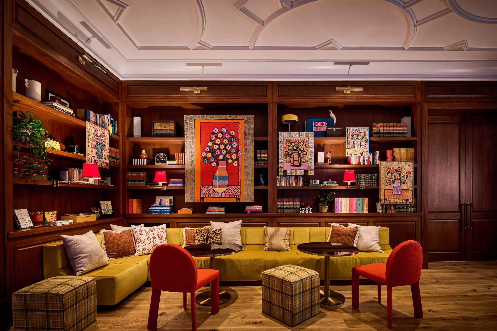 a colorful library with a green velvet couch and wooden bookshelves built into the wall