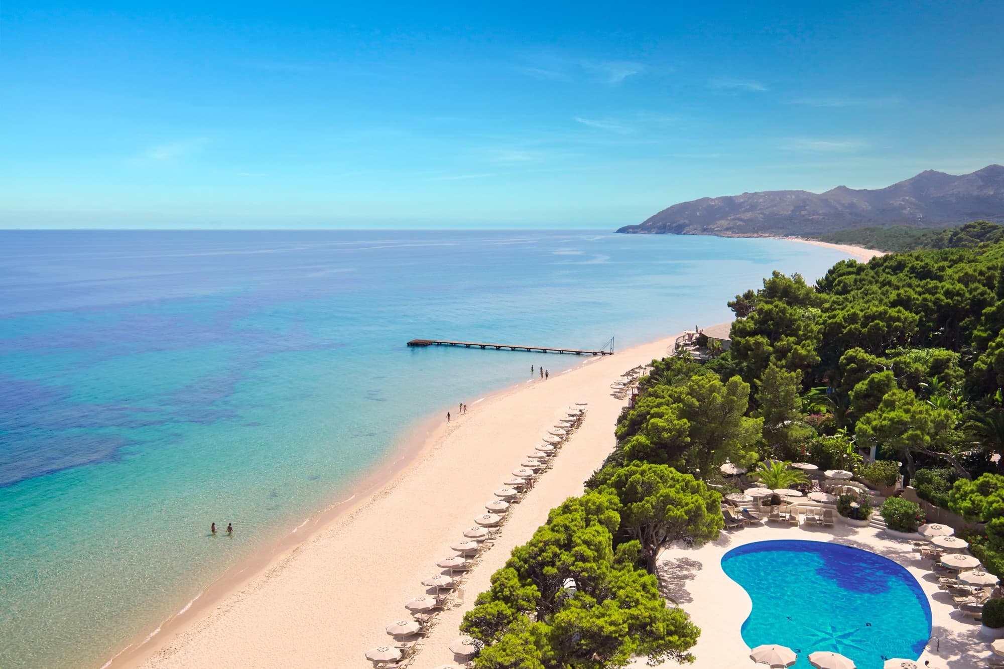 aerial view of a sandy beach dotted with beige umbrellas