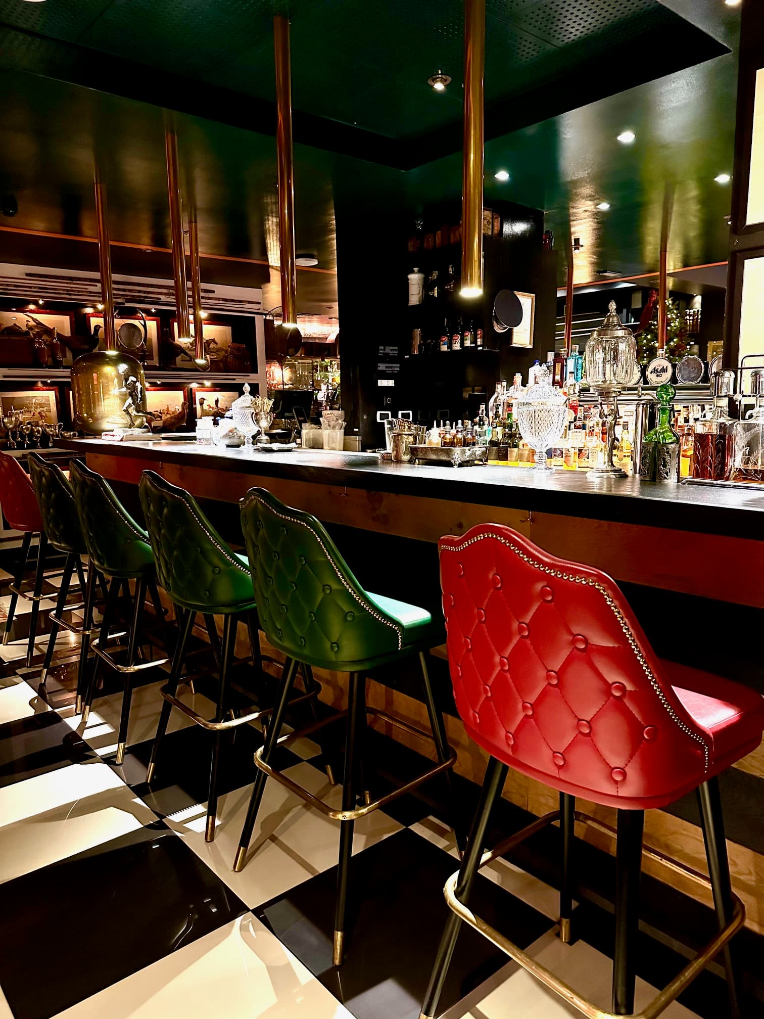 An indoor bar with red and green chairs