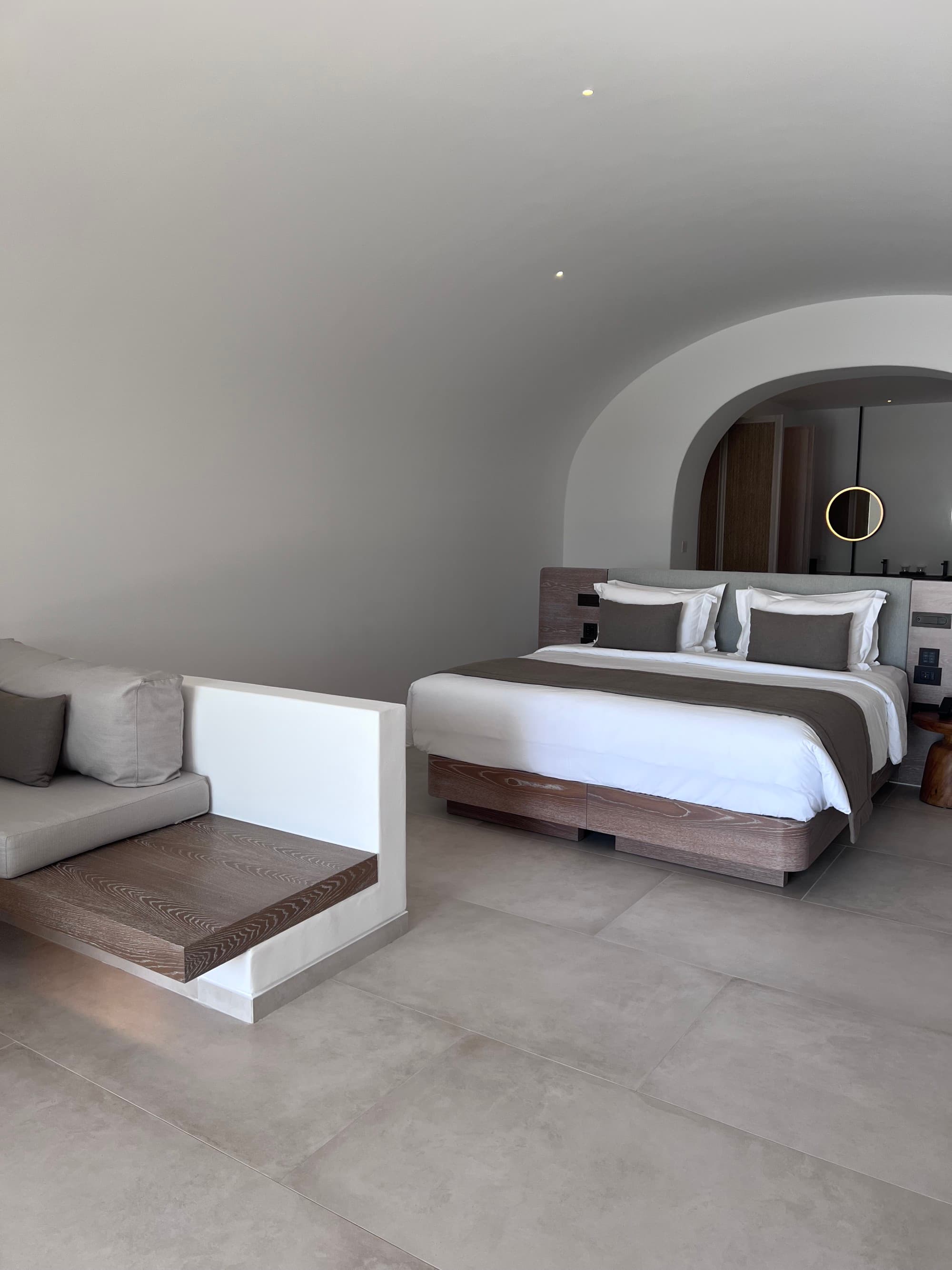 gray minimalist hotel room with a bed covered in white sheets