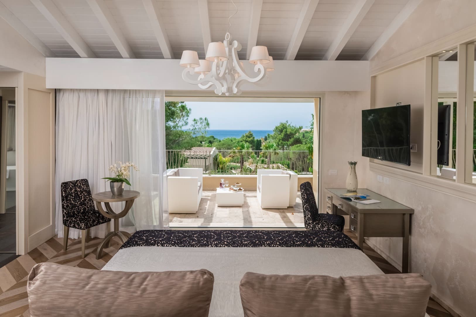 a living room with a white wooden chandelier overlooks the sea