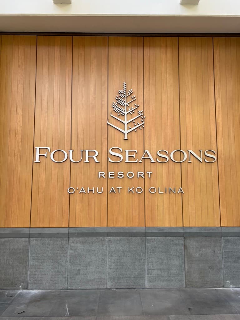 A wood-paneled wall with a sign reading "Four Seasons Resort Oahu at Ko Olina"