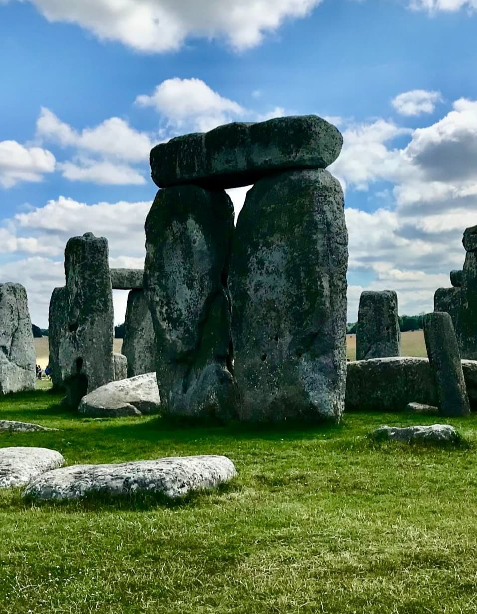 A view of the Stonehenge made up of large rock formations near a grassy lawn.