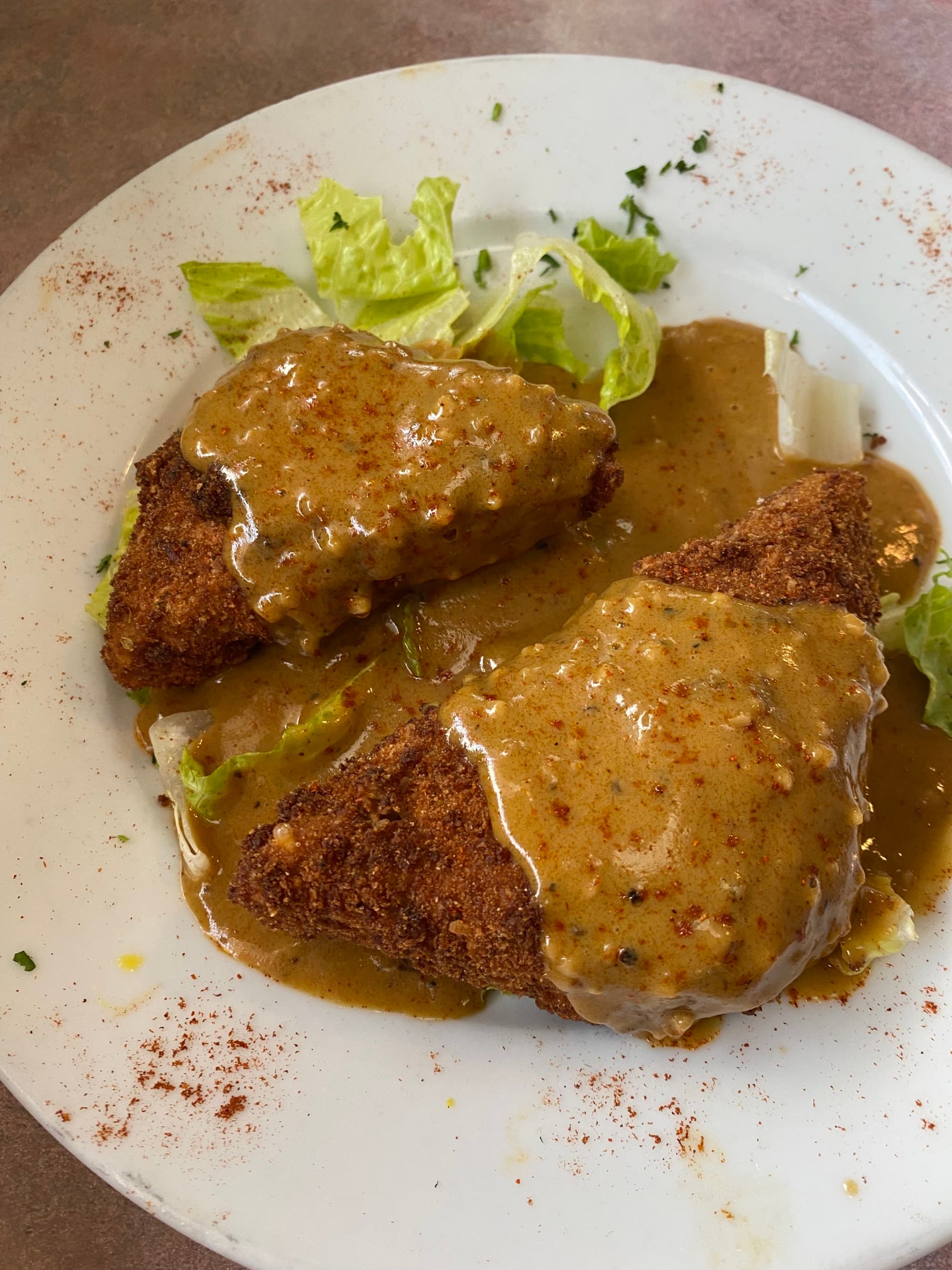 A white plate of fried chicken with sauce