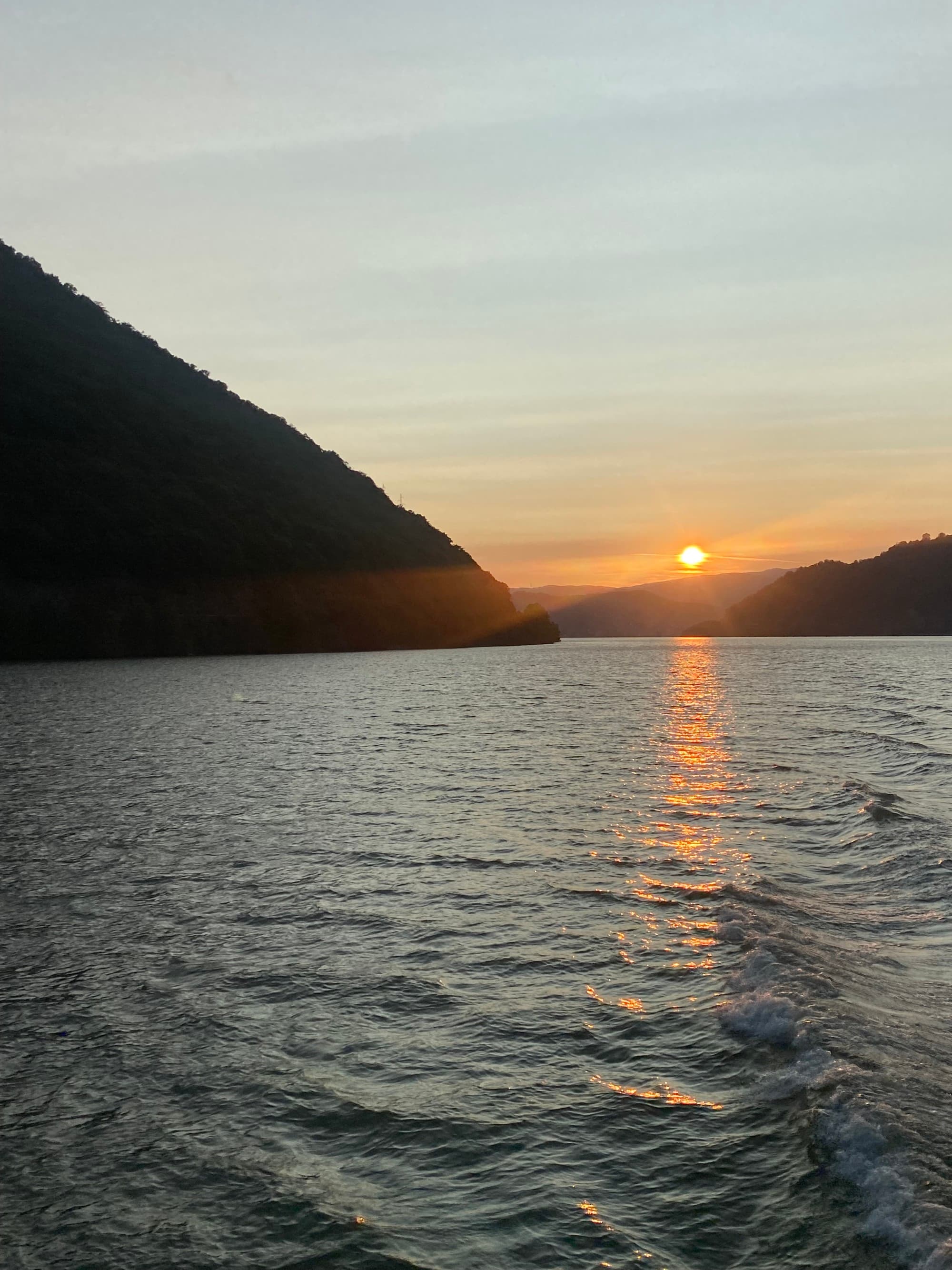 This image depicts a sunset over a river with mountains in the surrounding area.