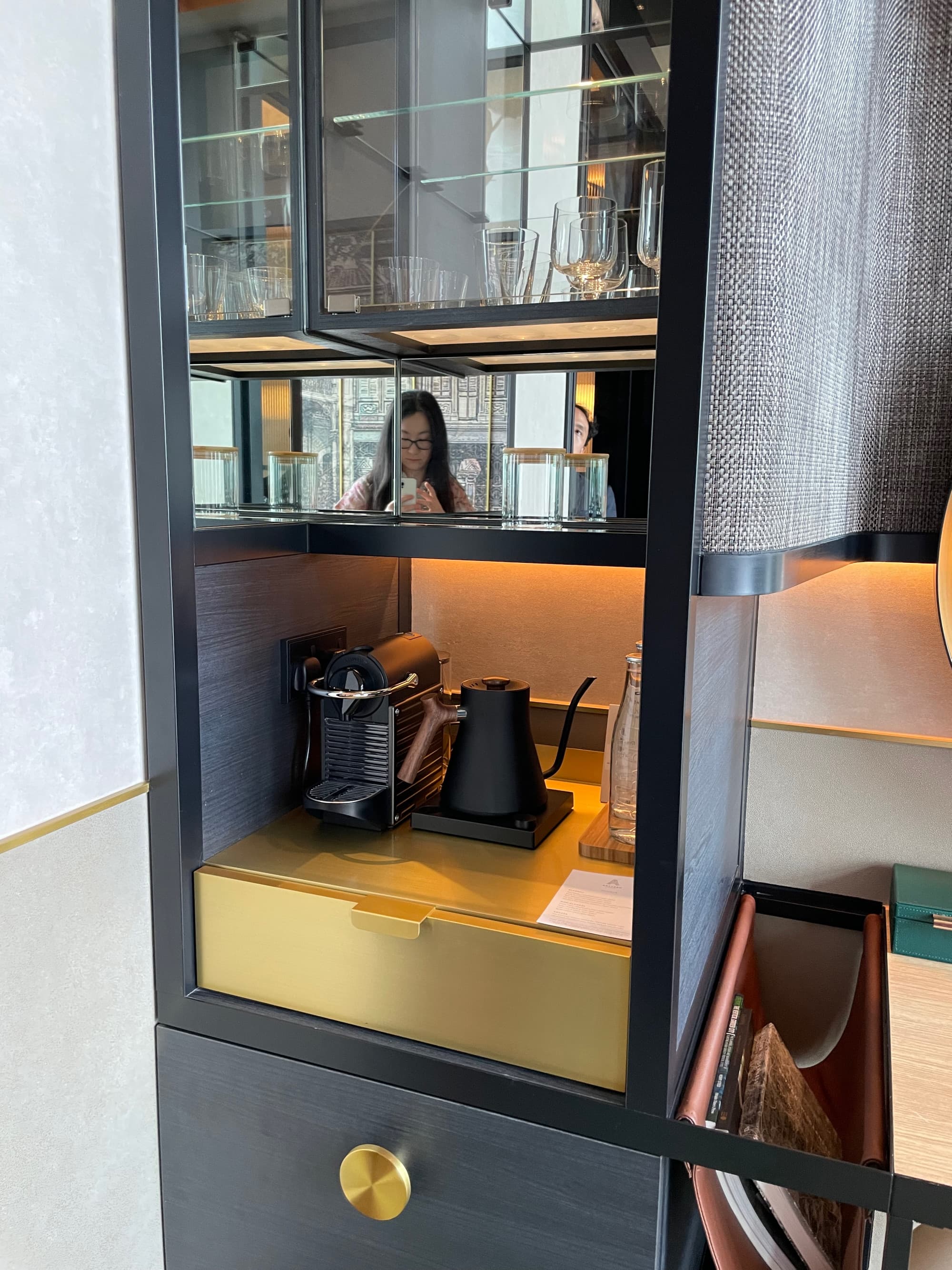 A picture of a black cabinet with gold fixtures in a hotel room with a Nespresso machine