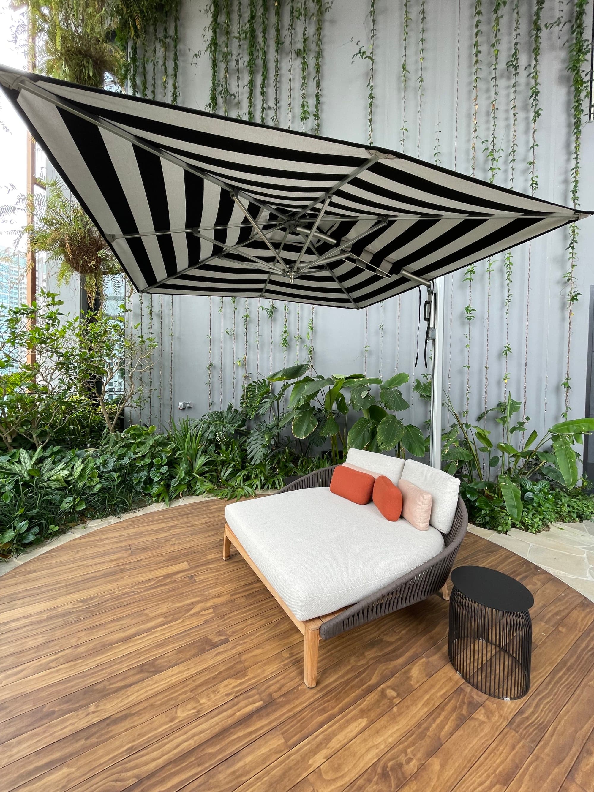 A wooden deck with a lounge chair and large black and white umbrella