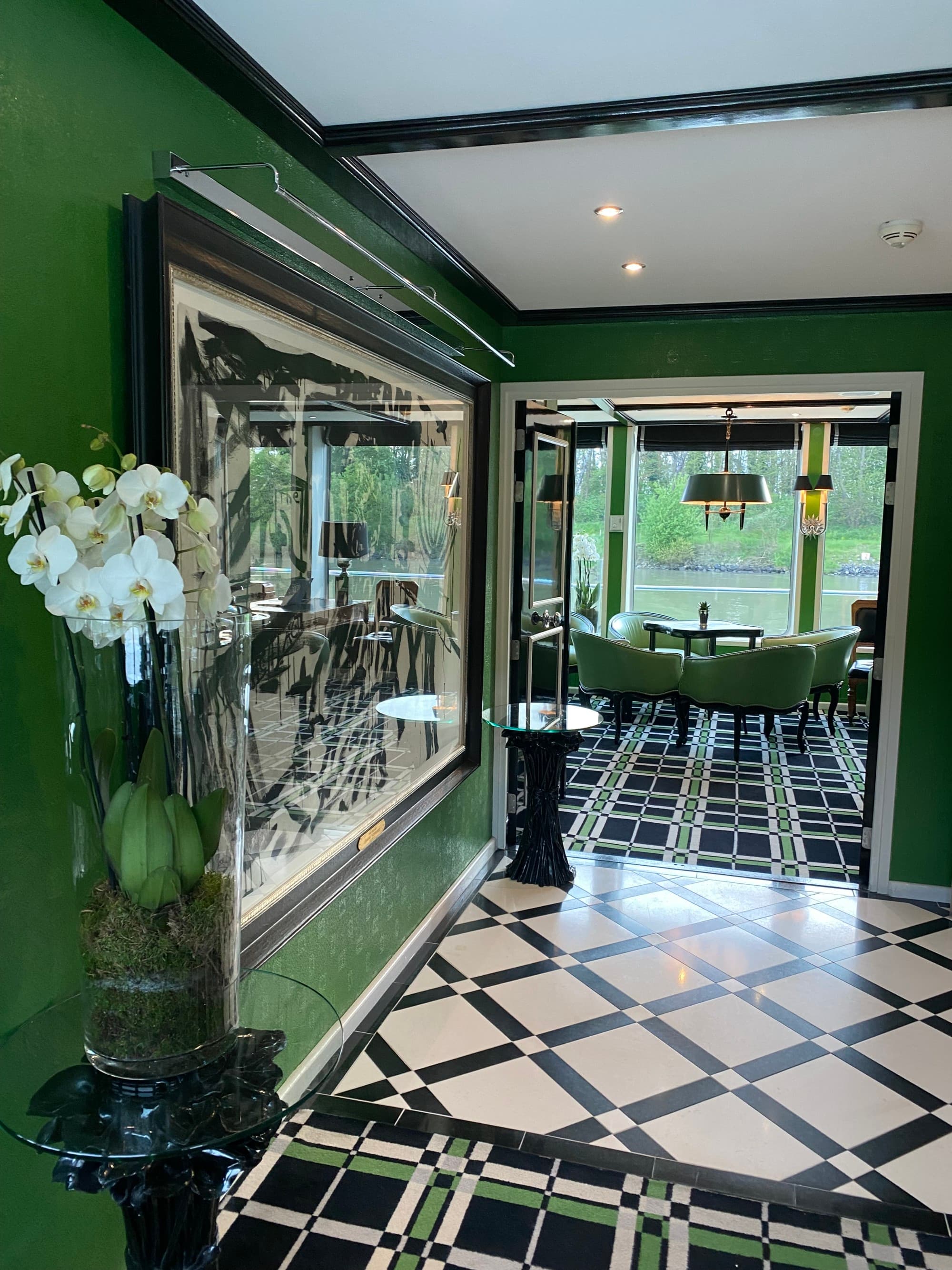 Inside the cruise ship of the lobby and sitting room, decorated with green walls and furniture, and black and white patterned floors.