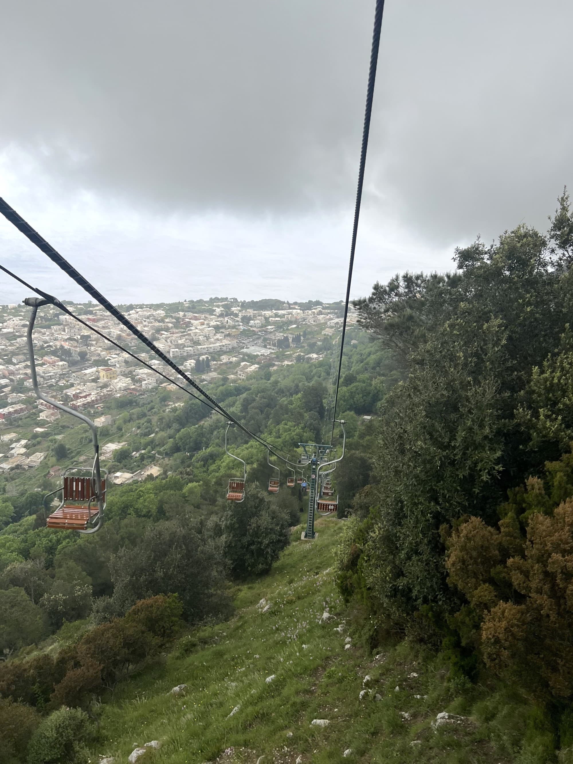 A chairlift above green hills and a town