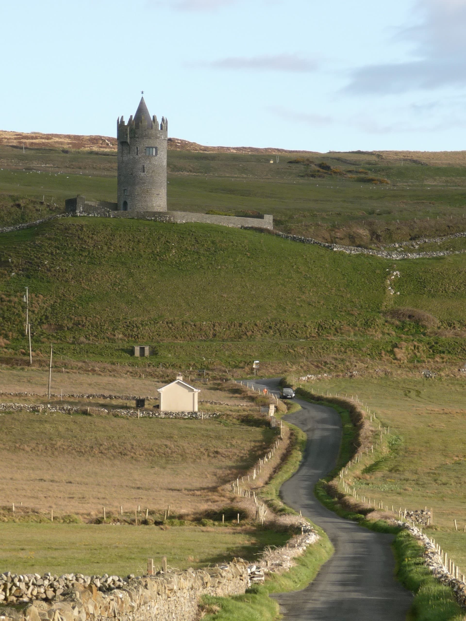 Green fields with a small castle in the distance during the daytime