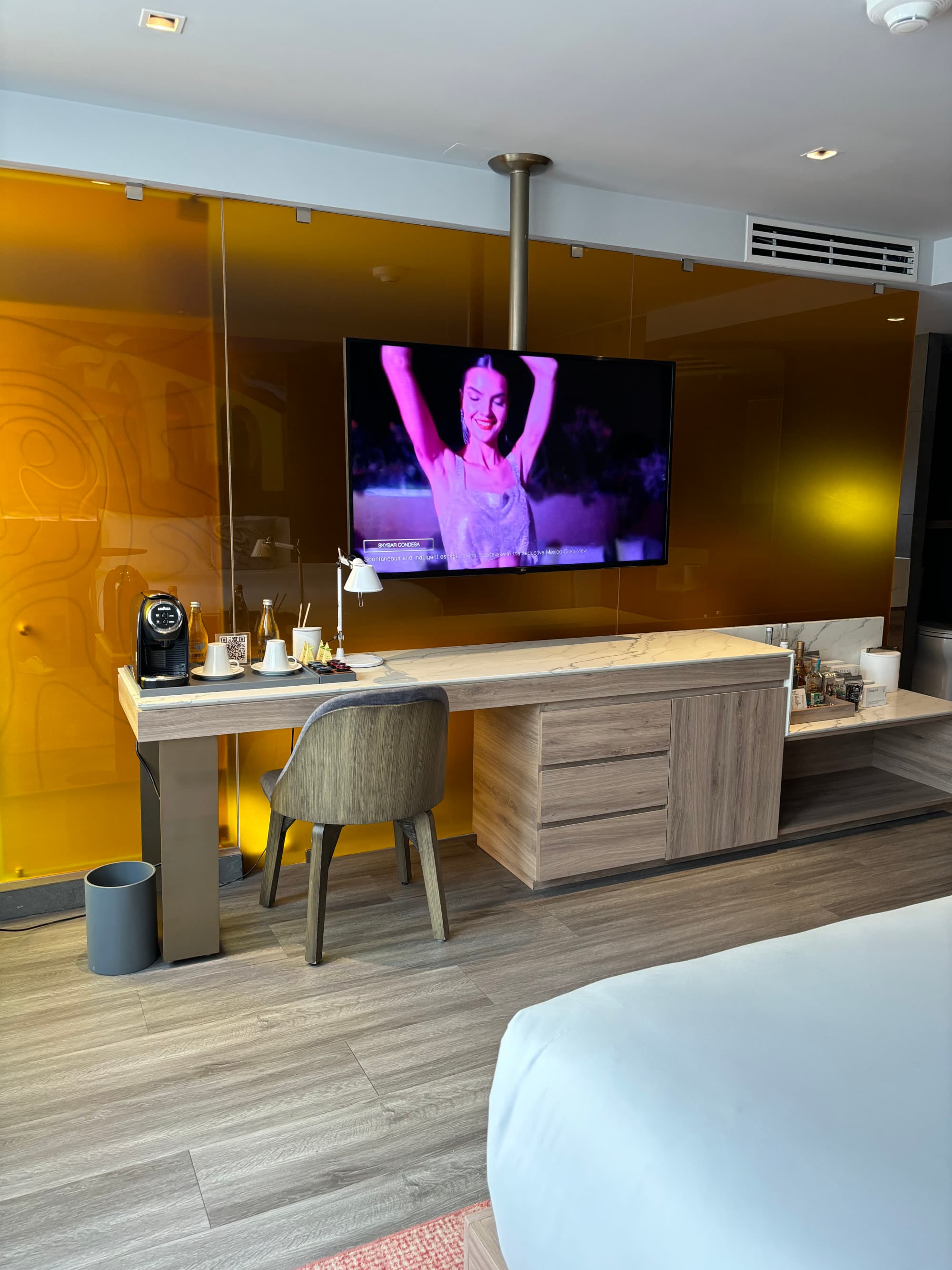 Inside one of the hotel's rooms with a large, flat screen t.v. and a wooden desk and chair.