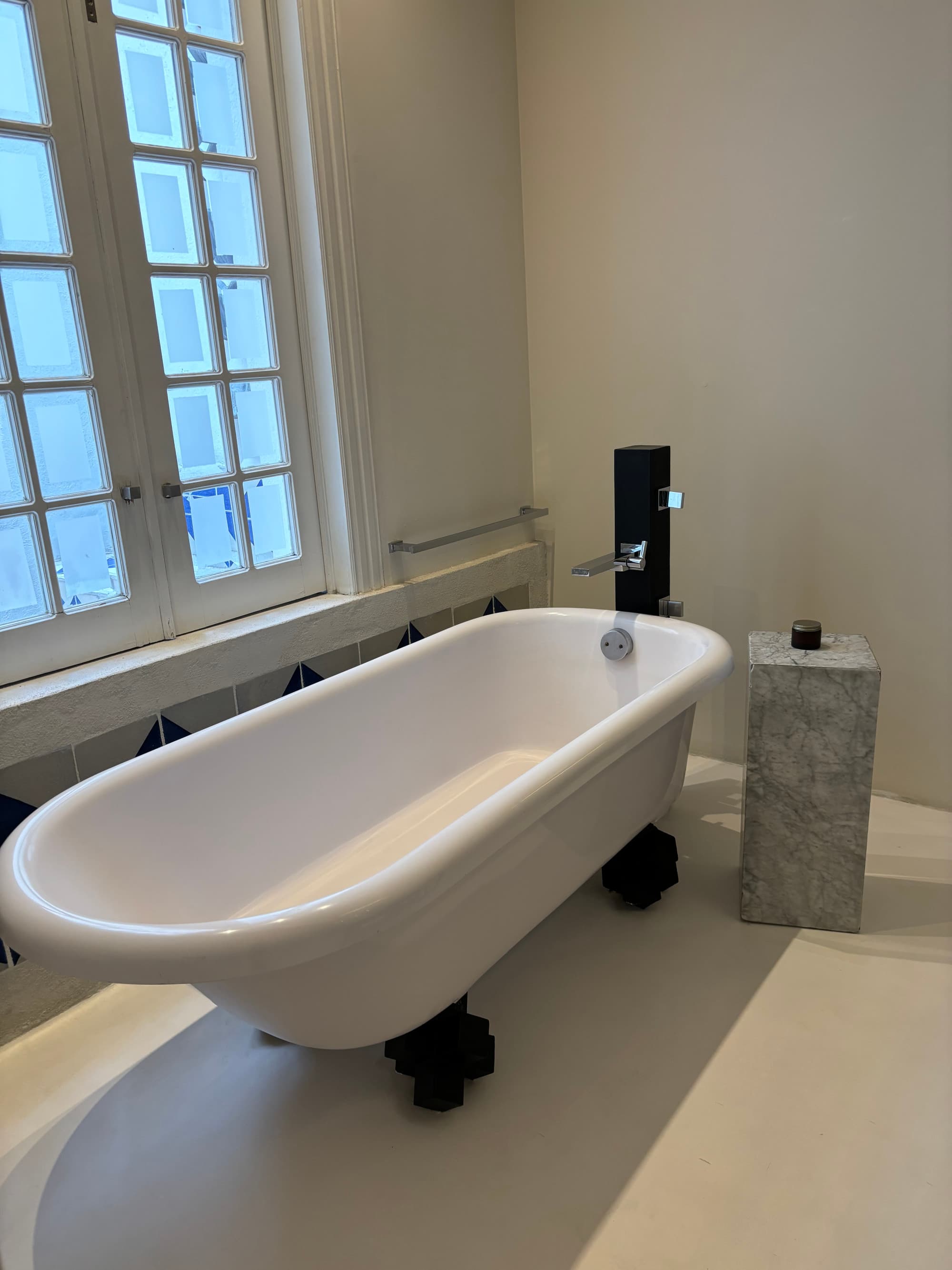 A white, clawfoot bathtub in a hotel bathroom