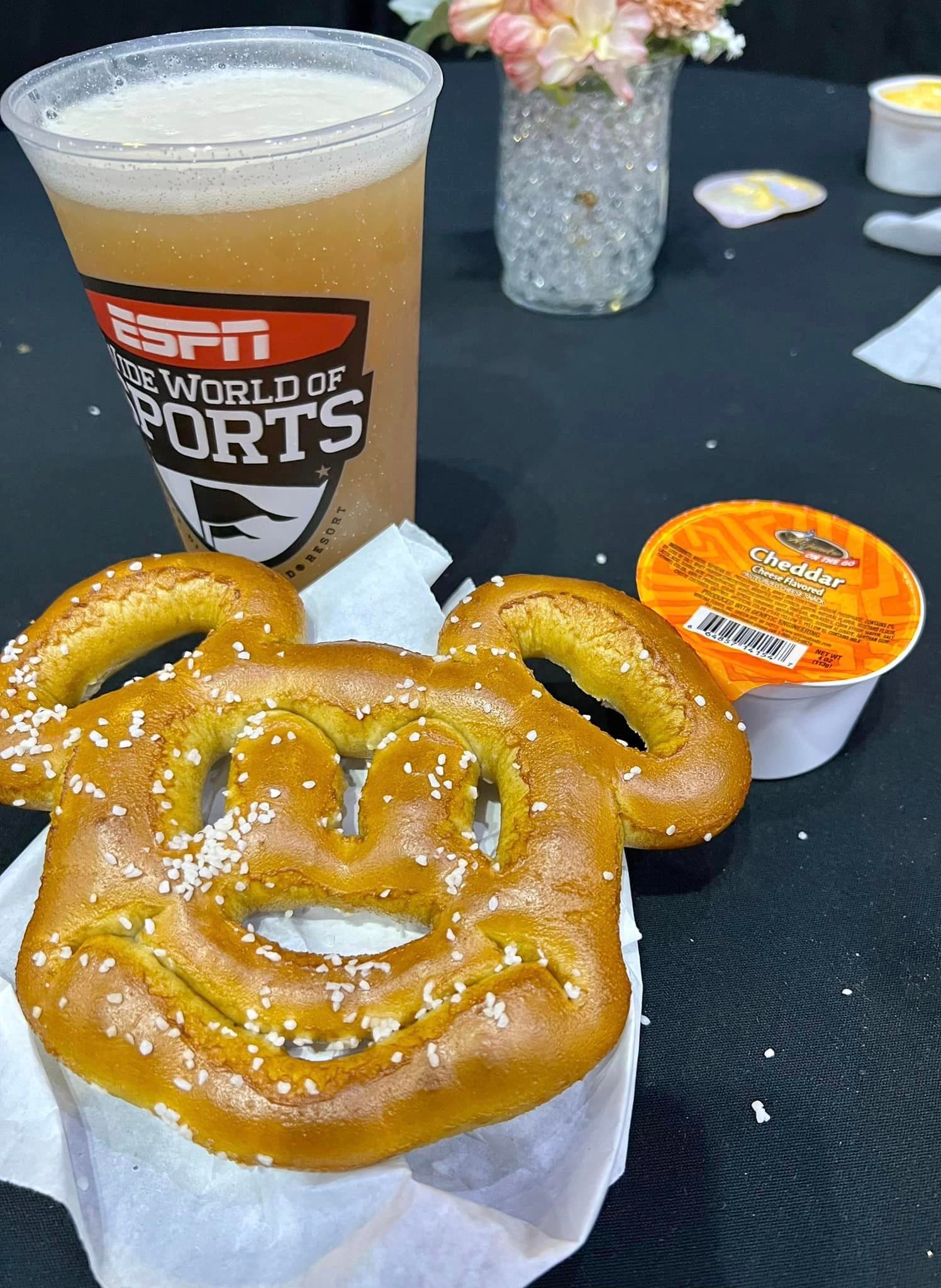 A character-shaped pretzel on a napkin in front of a plastic cup of beer