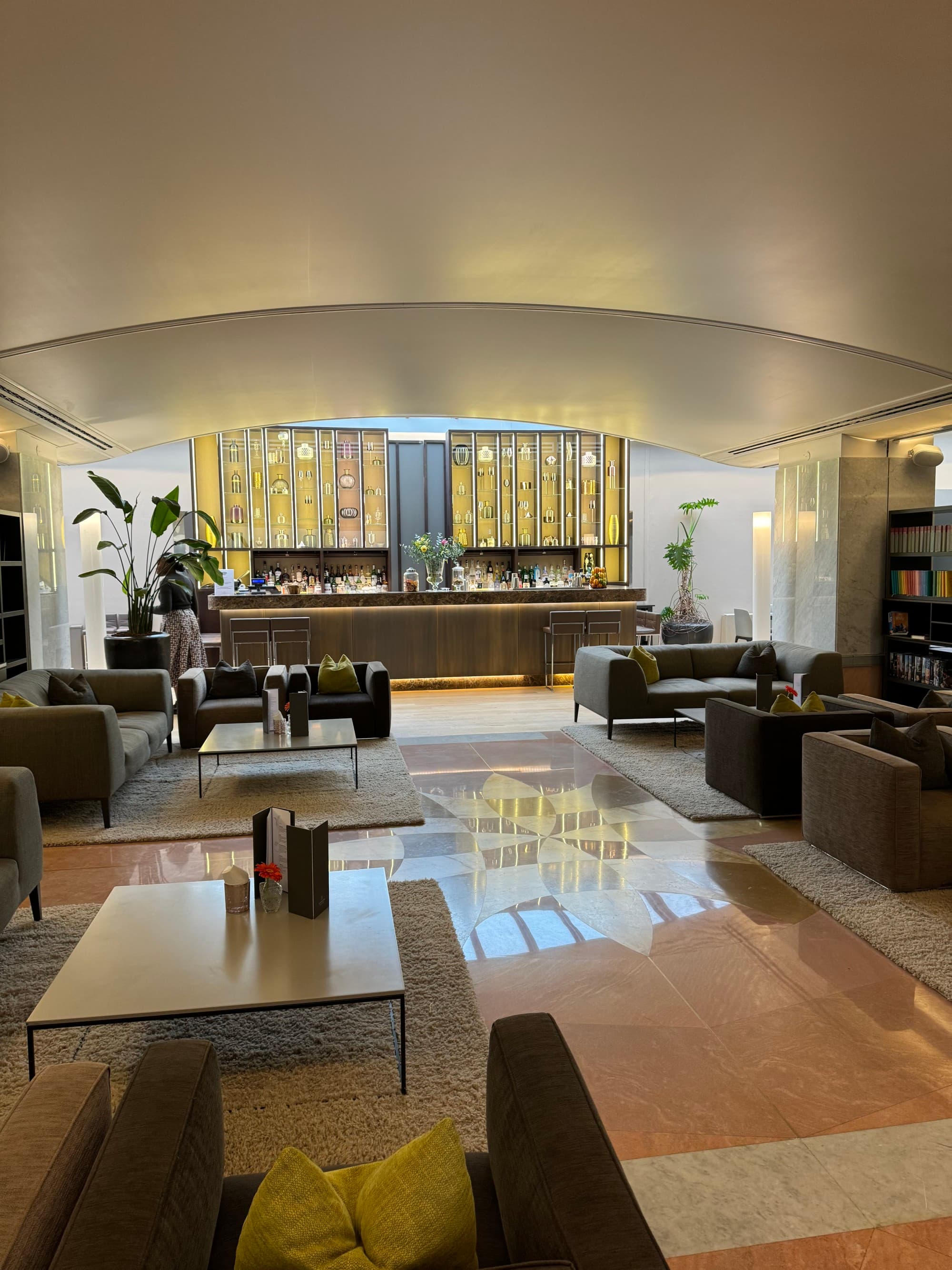 A cozy hotel bar with small couches and shiny tiled floors.