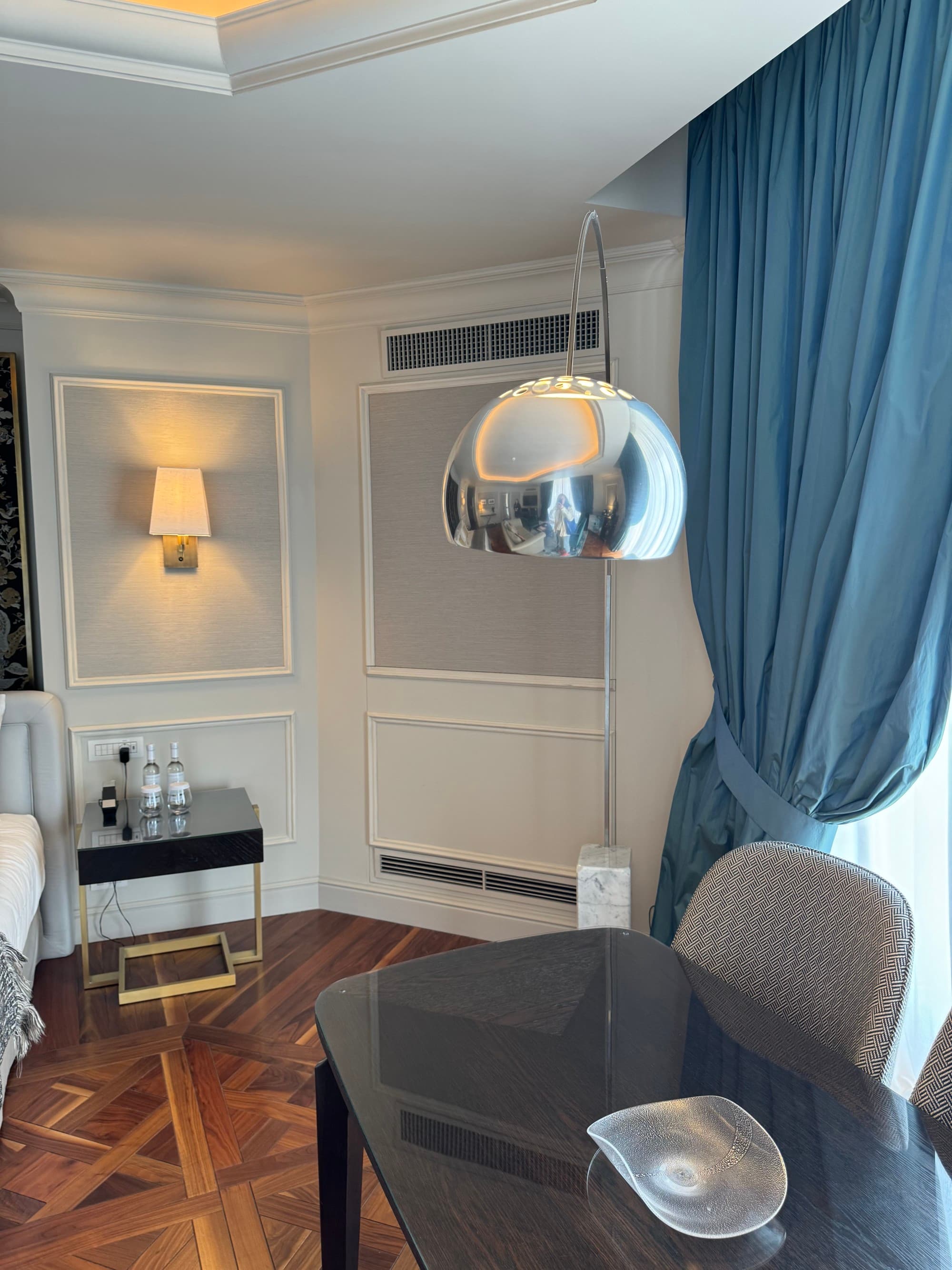 A hotel room desk with a chrome lamp hanging over it and a window behind it.