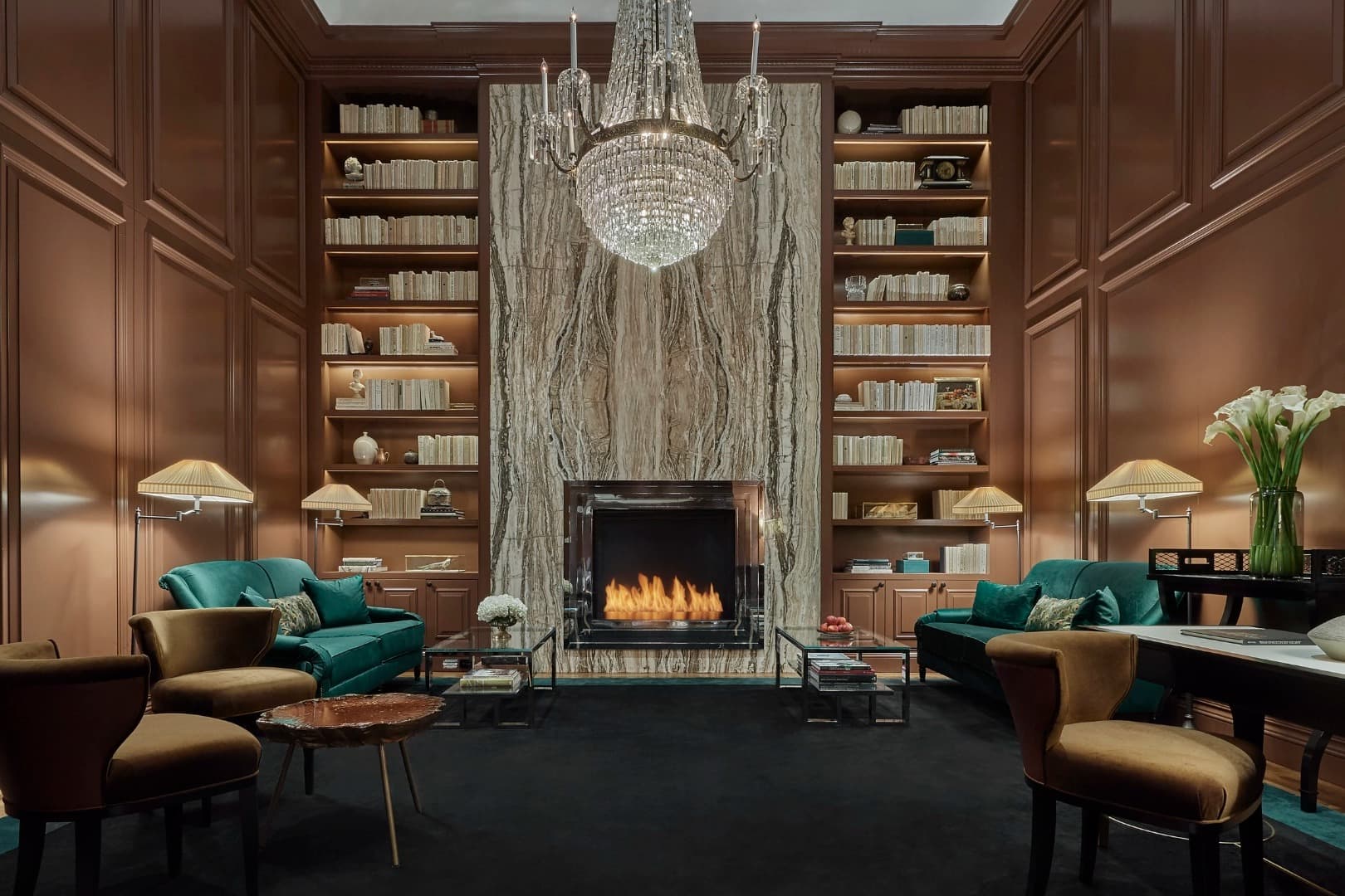 cozy library with marble fireplace and chandelier and wood paneled walls