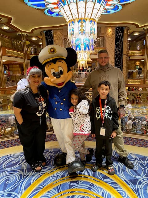 Family posing with Mickey Mouse aboard the Disney Cruise Line.