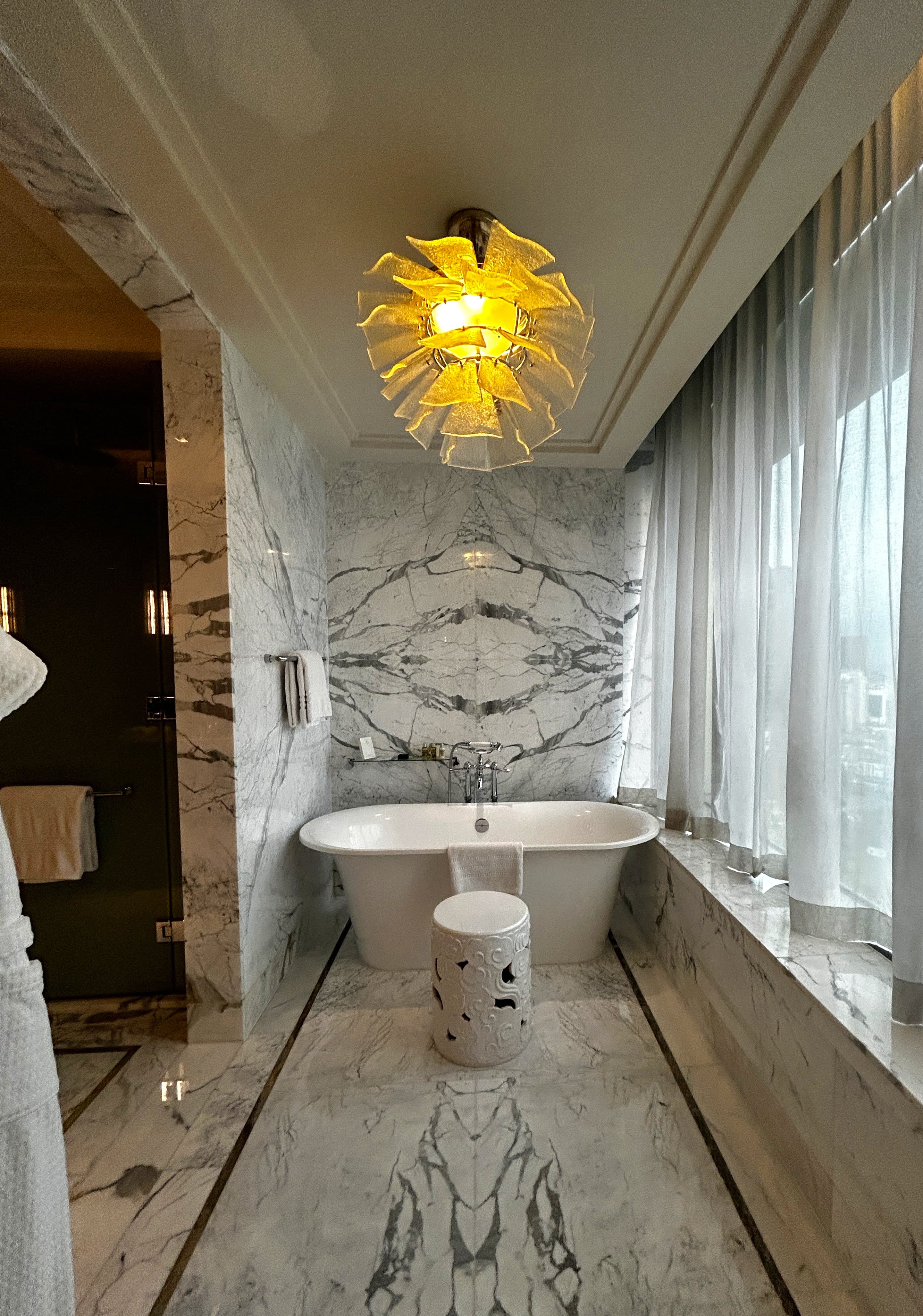 The bathroom of a hotel room at Four Seasons Jakarta with mobile flooring and walls, and a large white bath tub.