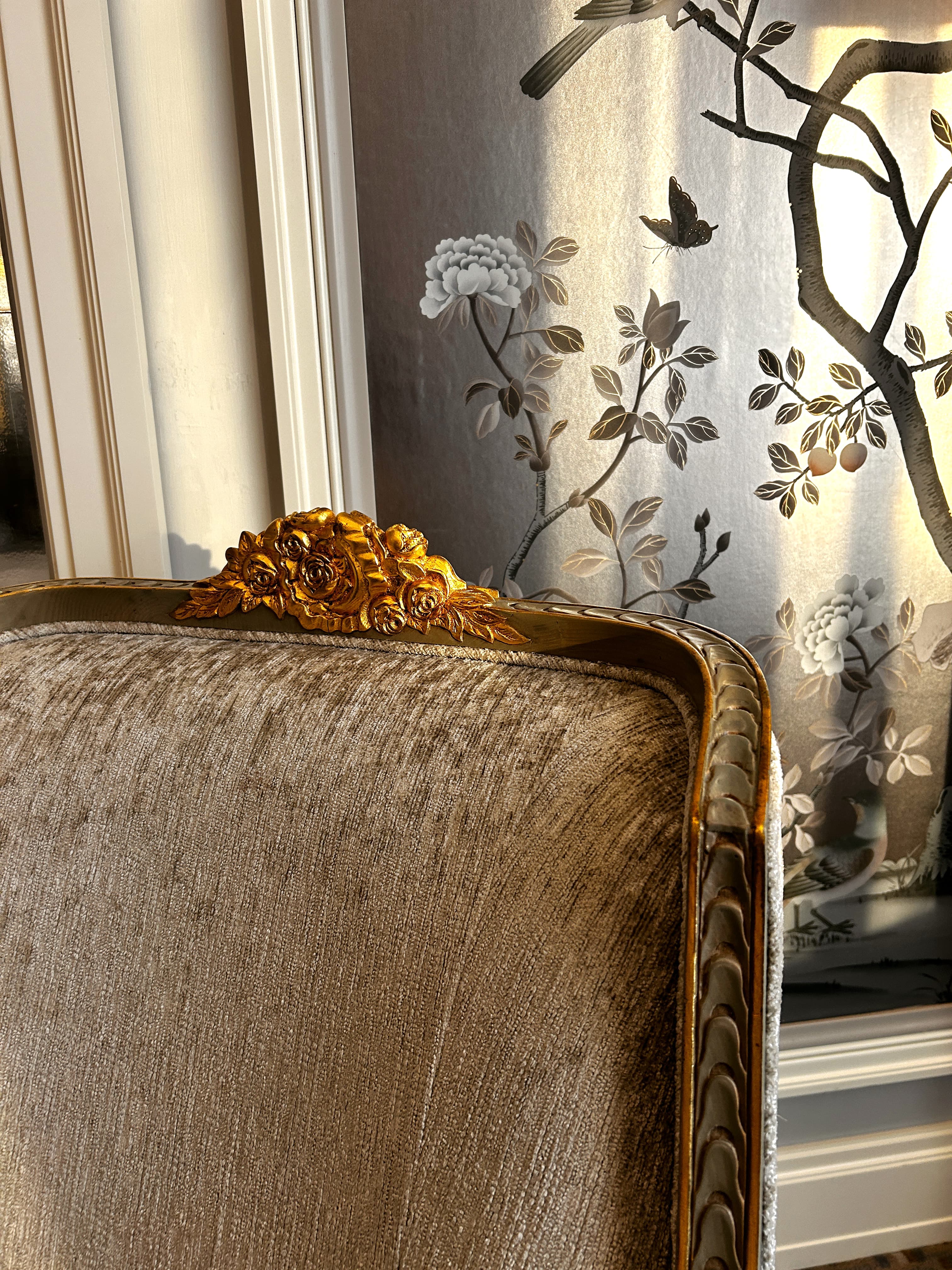 A close-up view of a gold embellishment on a tan chair.