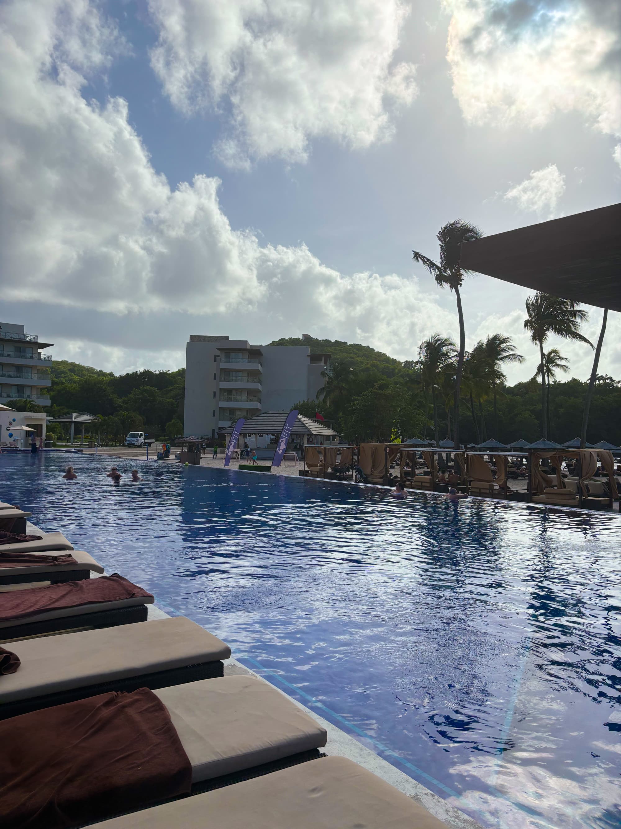 A poolside view of calm waters next to rows of loungers on a sunny day.