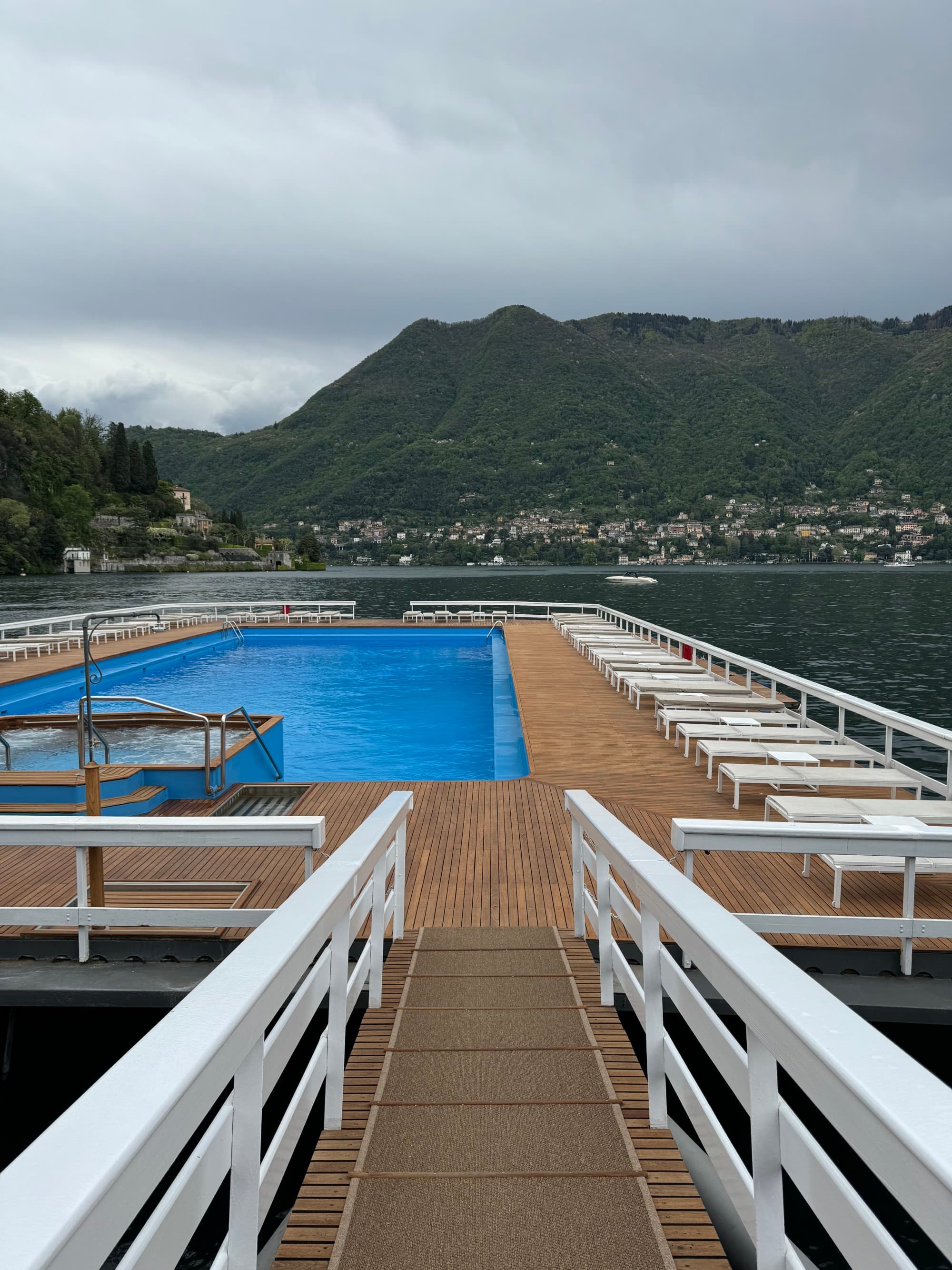 A walkway leads to a pool nestled off the coast on a cloudy day.