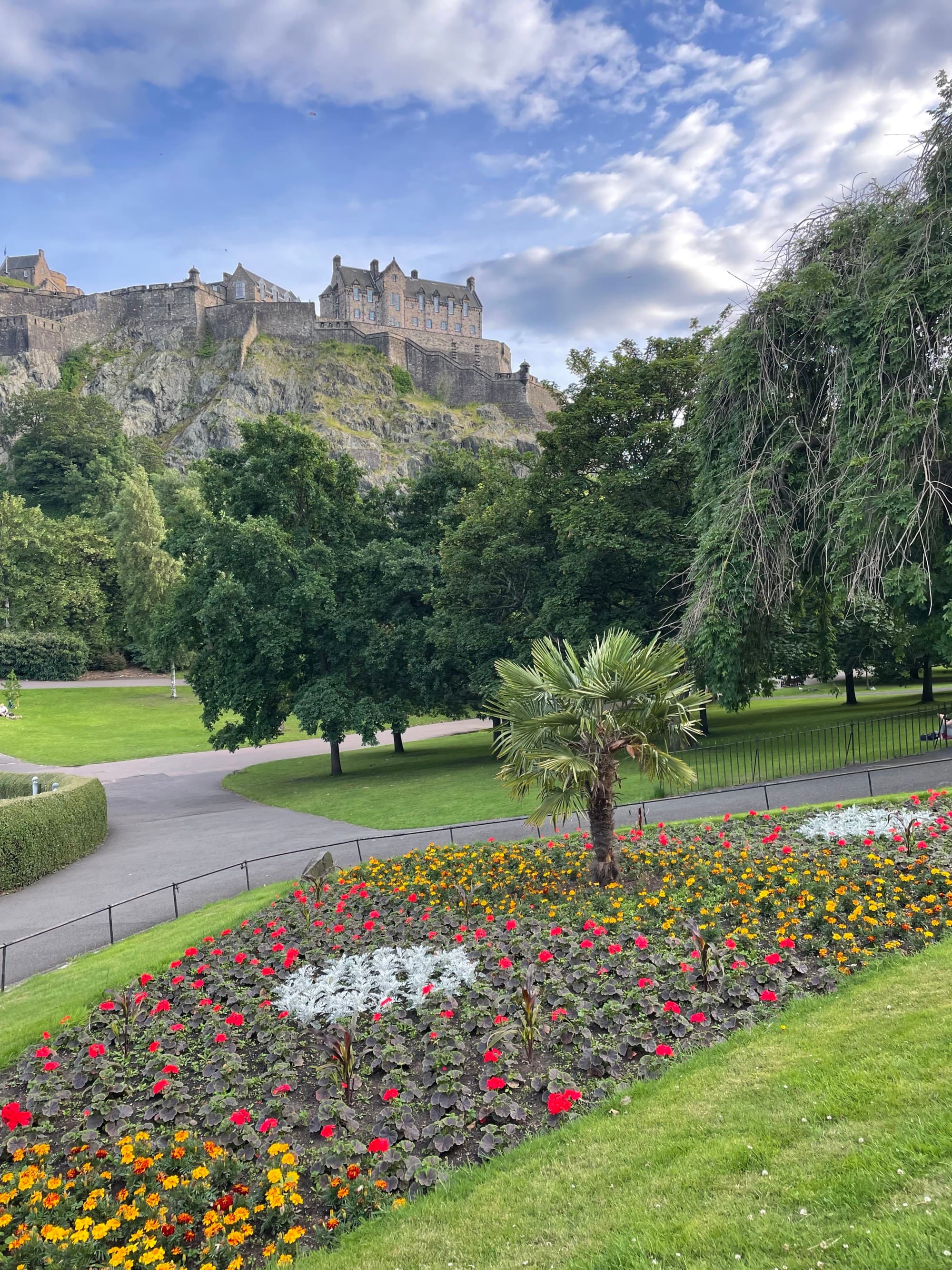 A hillside covered in green grass, trees and colorful flowers at the Princess Gardens in Edinburgh.