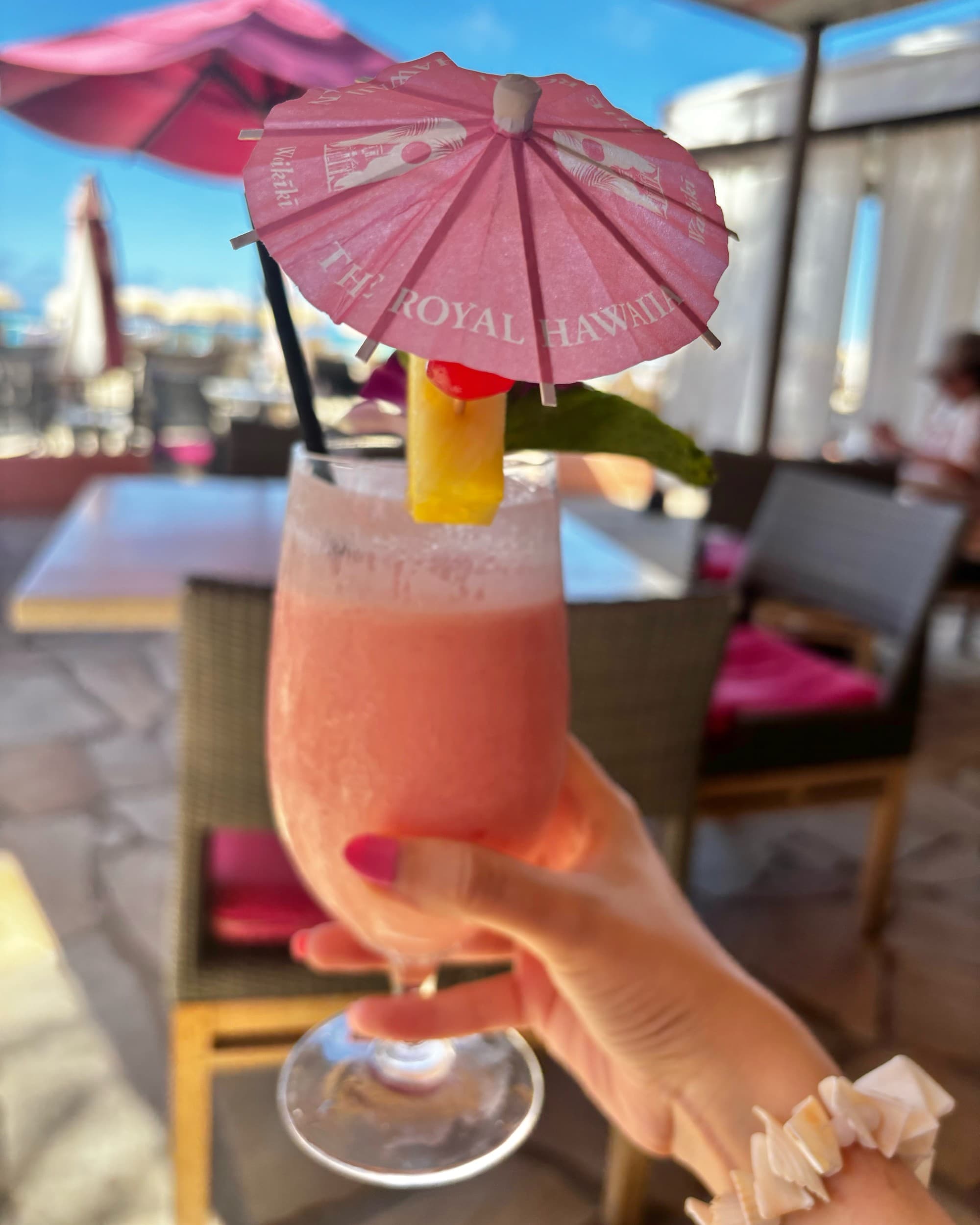 Hand holding a pink frozen drink with a pink umbrella.