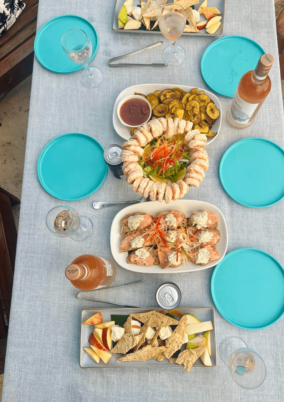 Aerial view of dining set up with various dishes, a bottle of wine and bright blue dishes.