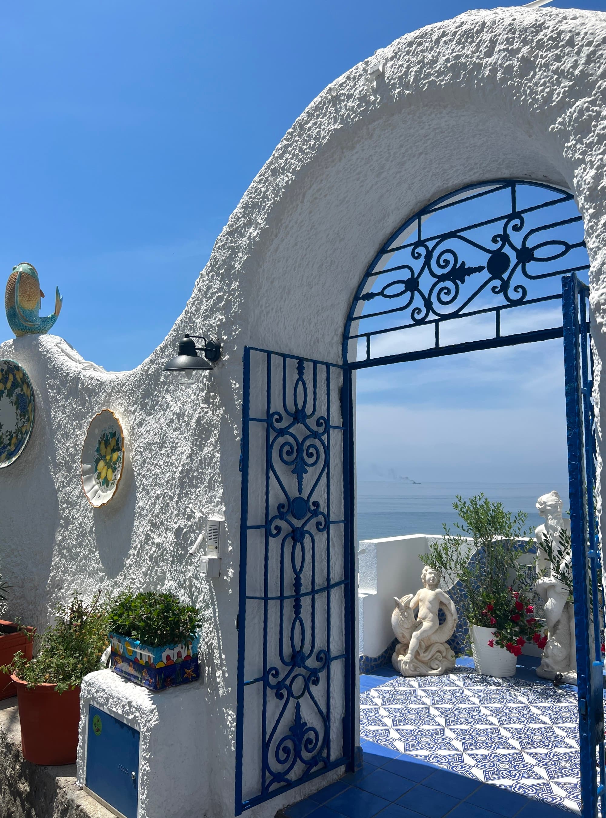 An arched, while wall with a blue gate inside it