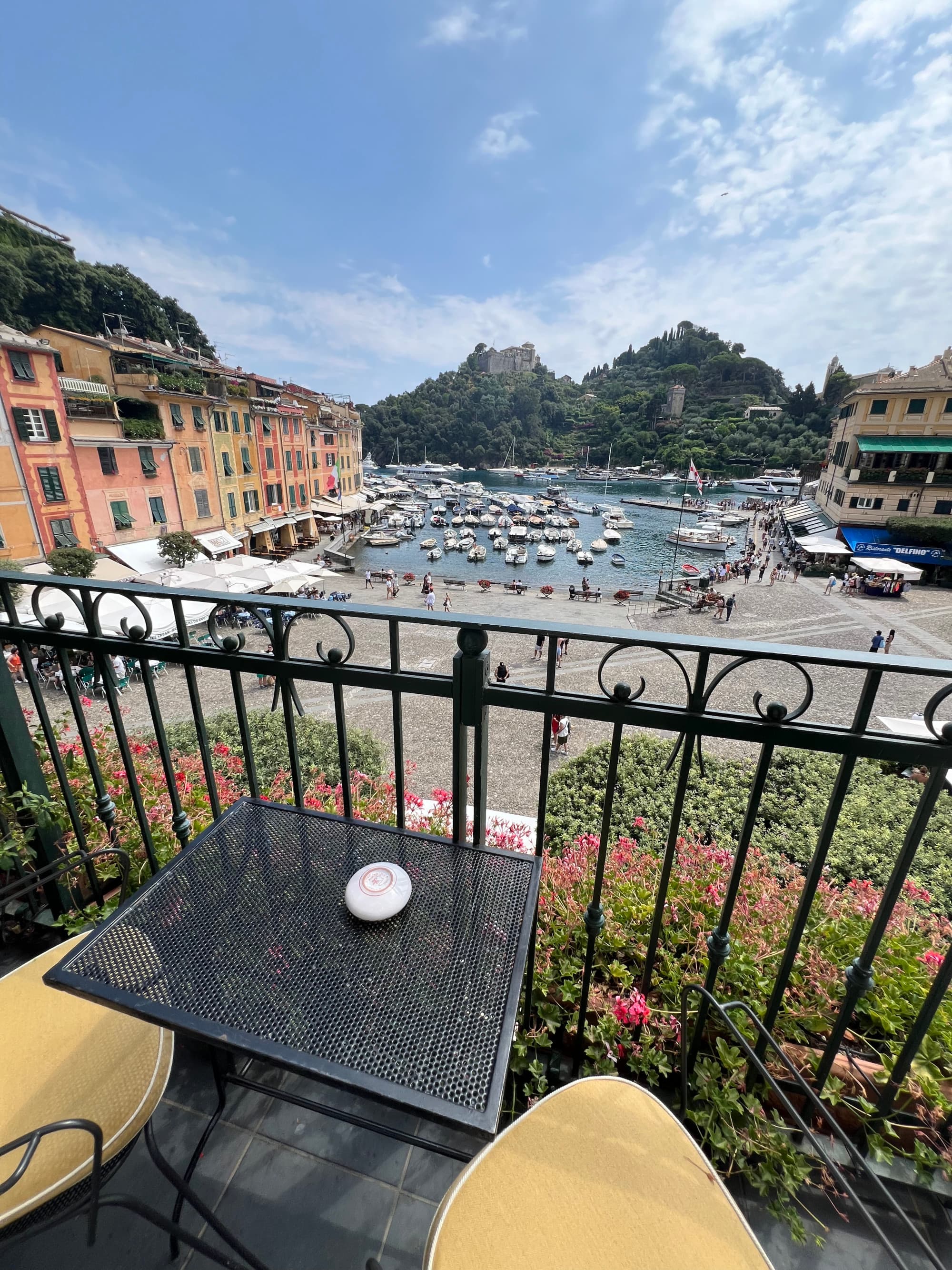 The view from a terrace overlooking the street and boats docked at the shore on a sunny day.