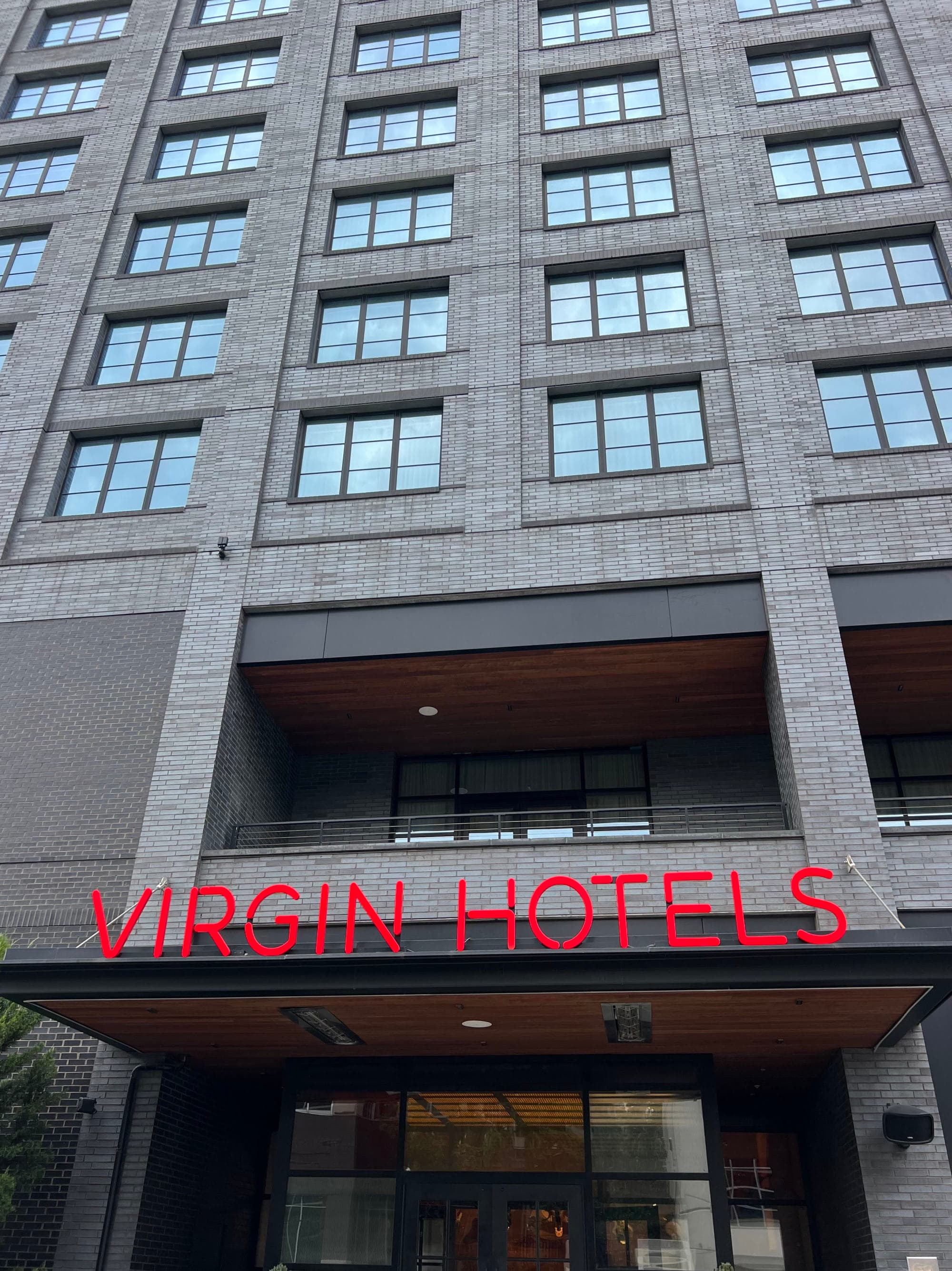 The exterior of a tall building with a sign reading "Virgin Hotels" in red lettering