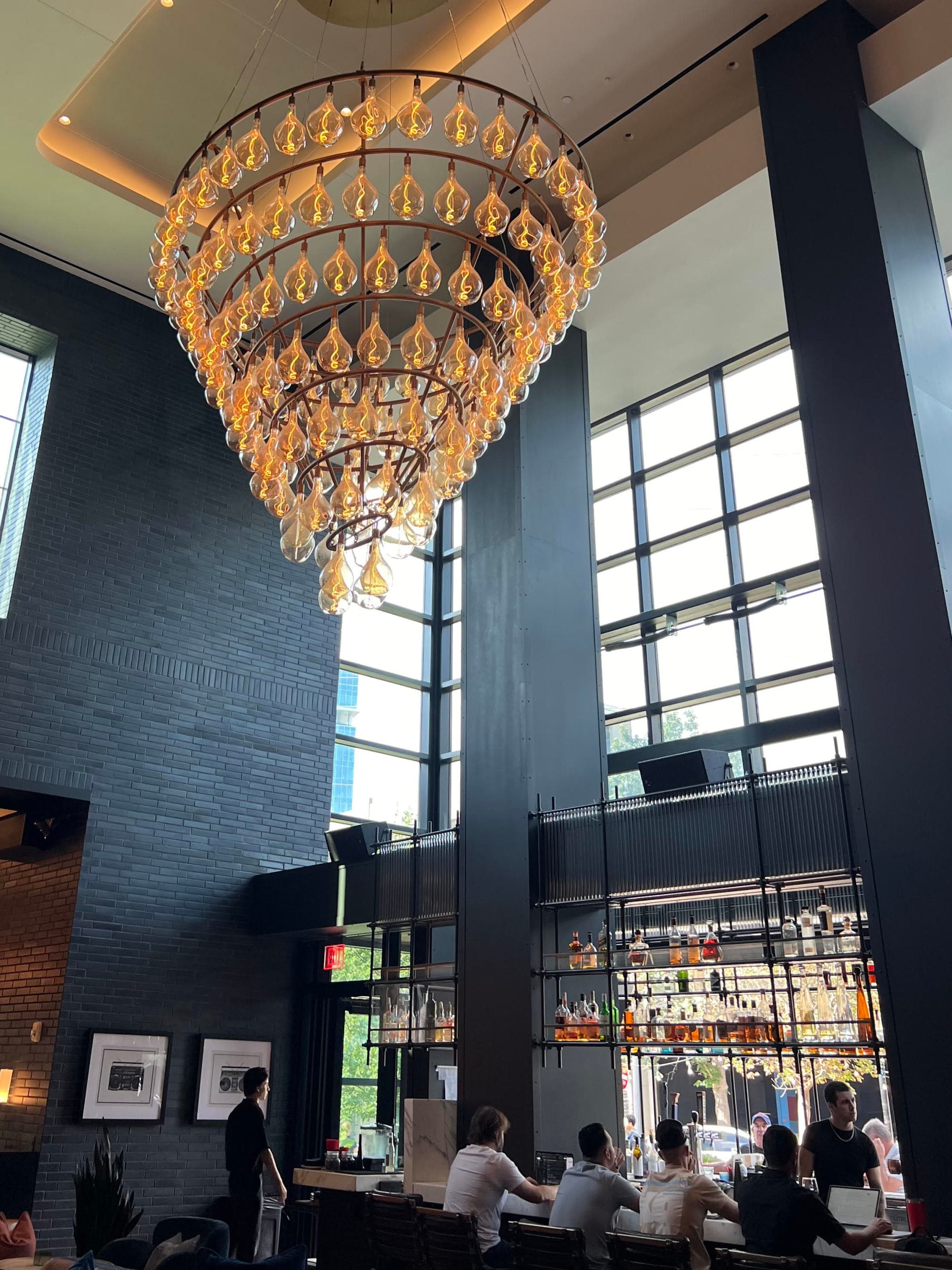 People sitting at a bar with a large chandelier hanging from the ceiling above them