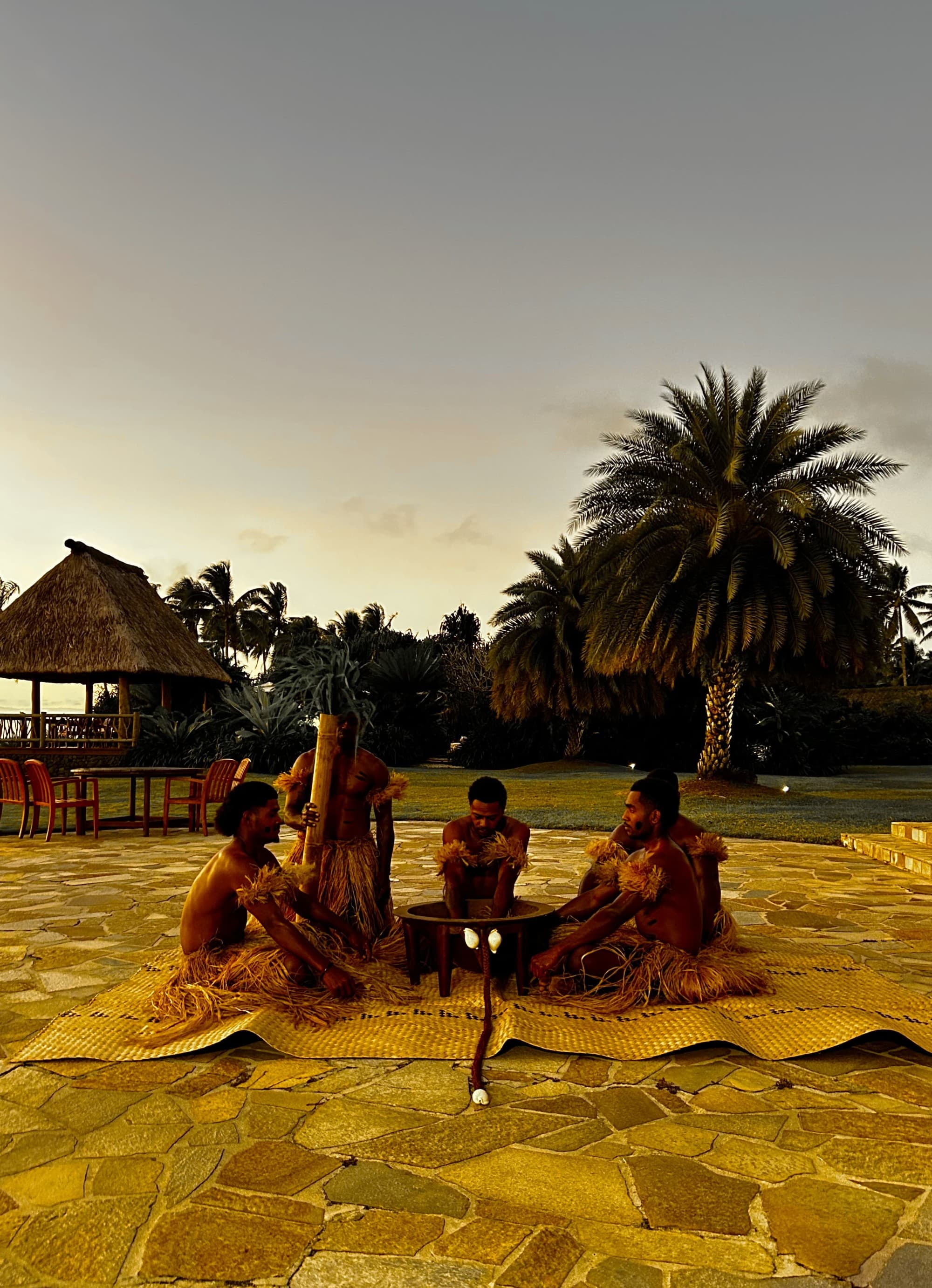 A group of people sitting in a circle on the ground during the sunset