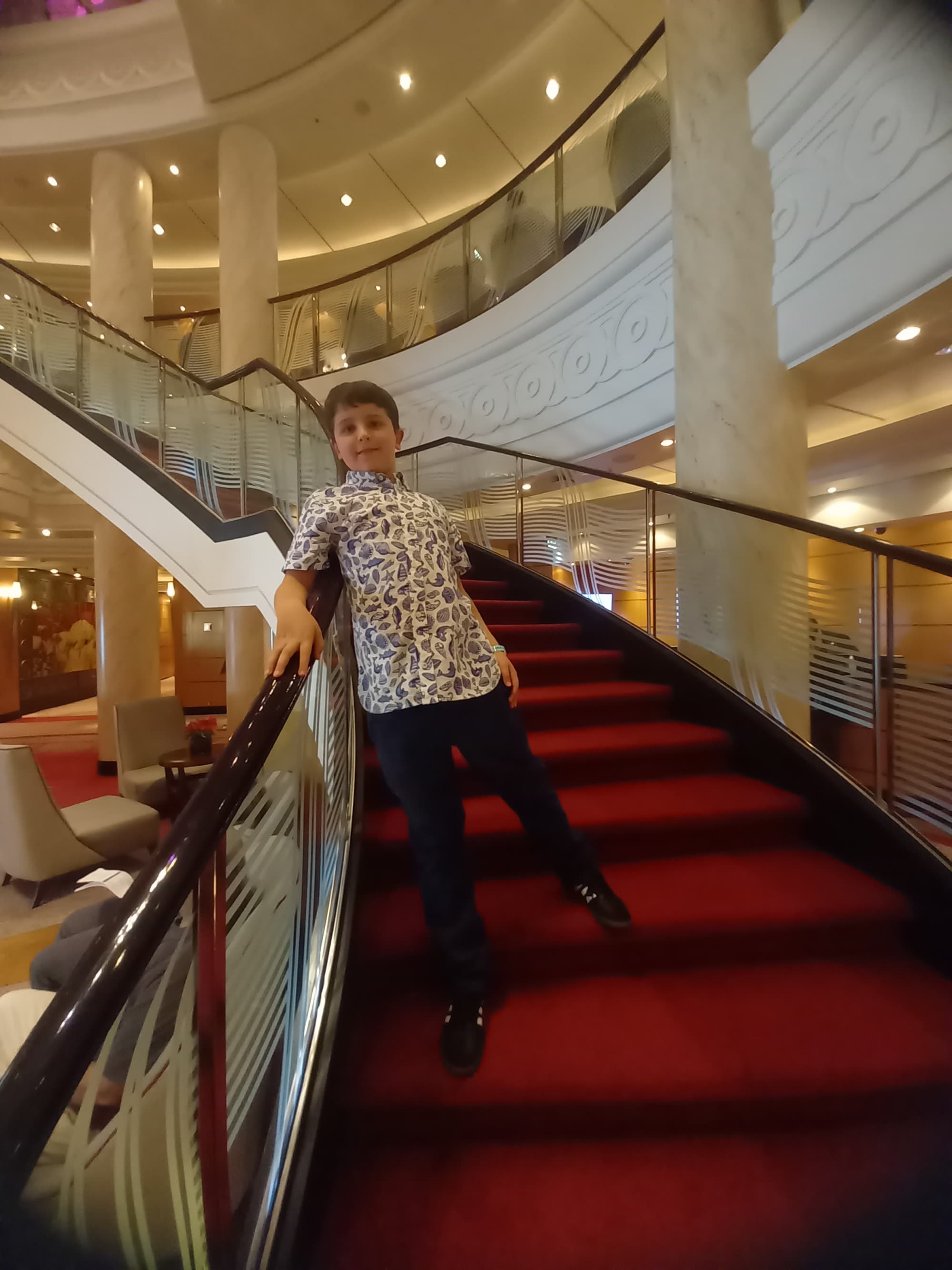 A kid posing on red-carpeted stairs.