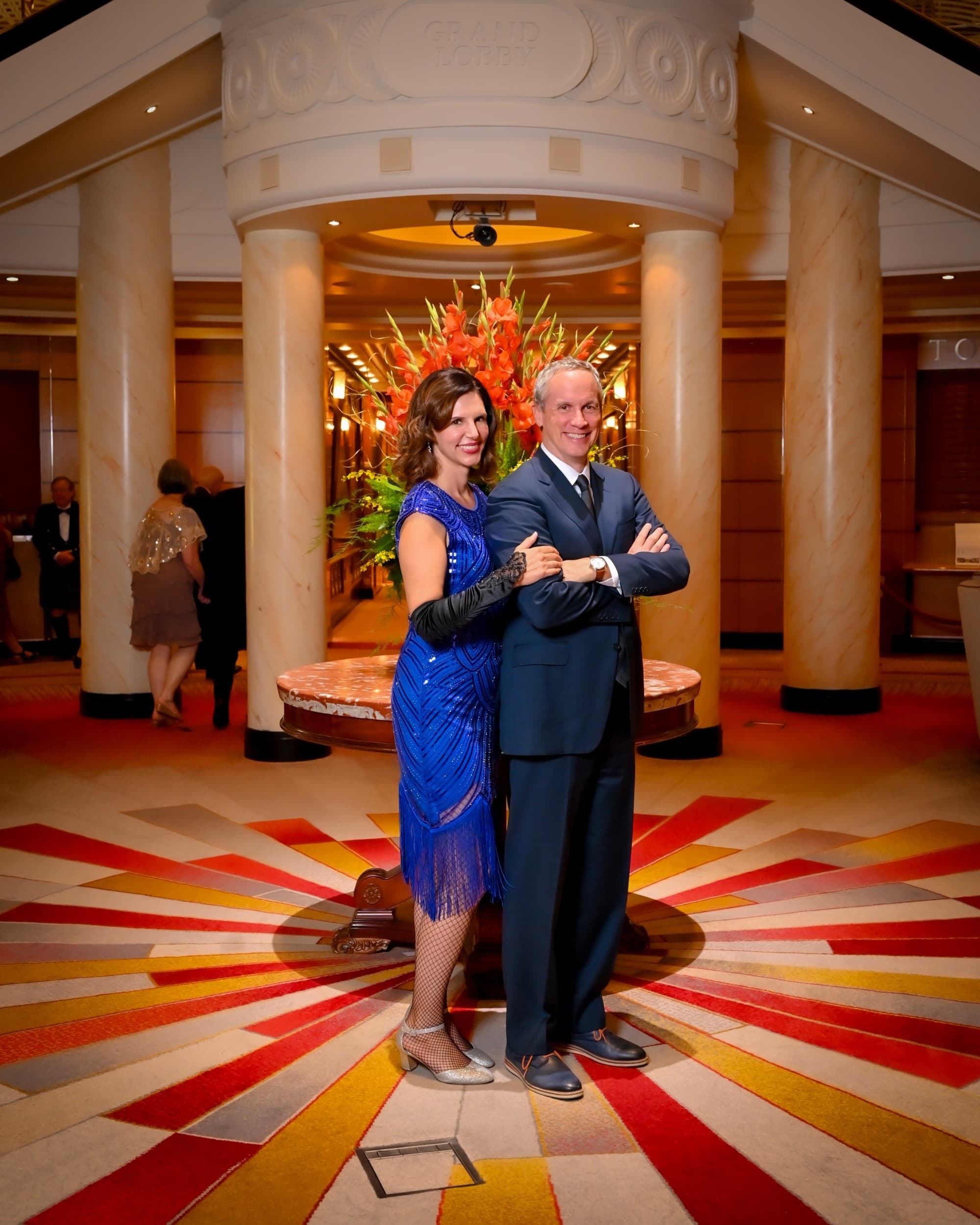 A couple posing in front of a table with a floral arrangement.